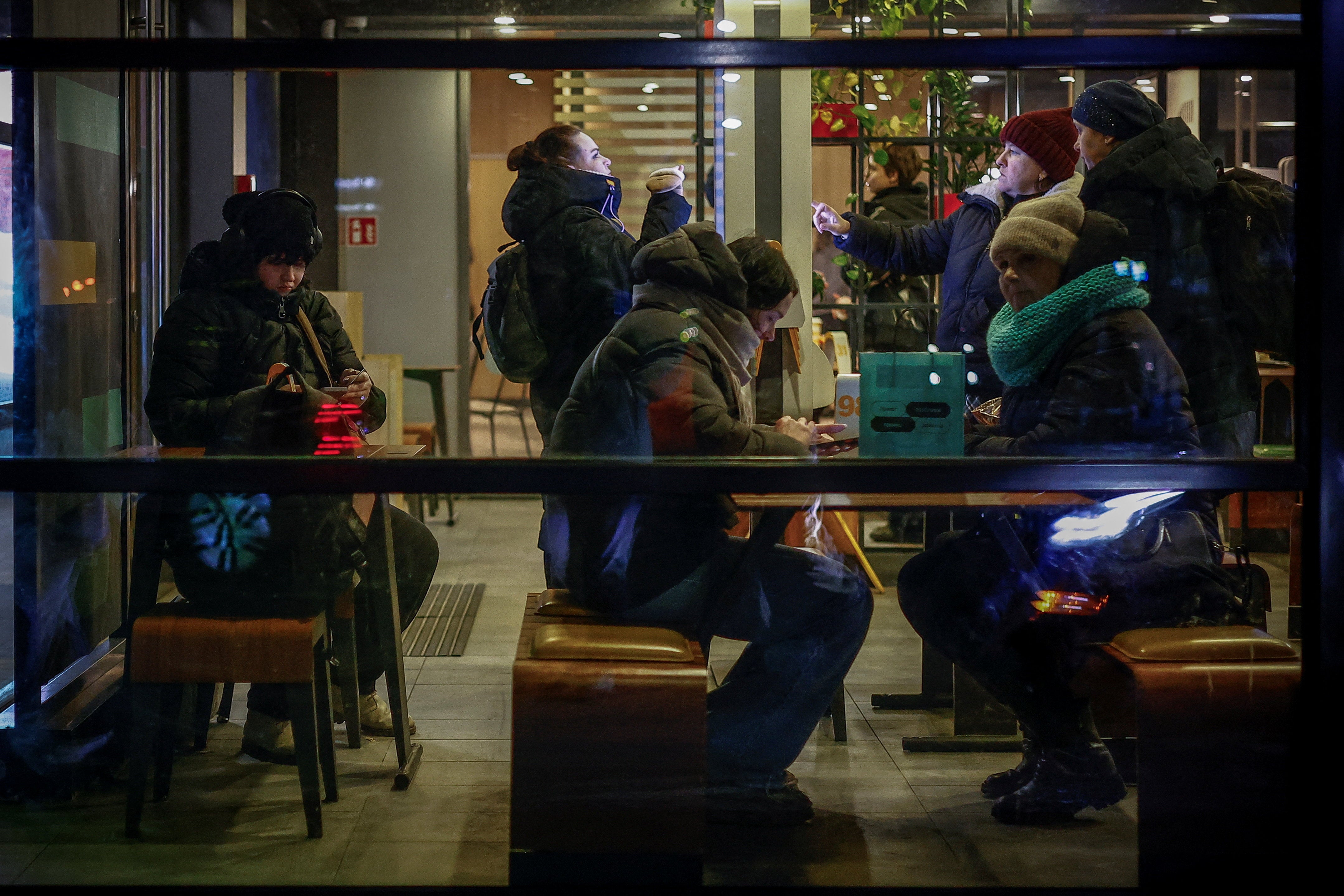 People warm up inside a restaurant during sub-zero temperatures following recent Russian missile and drone strikes on civilian infrastructure,