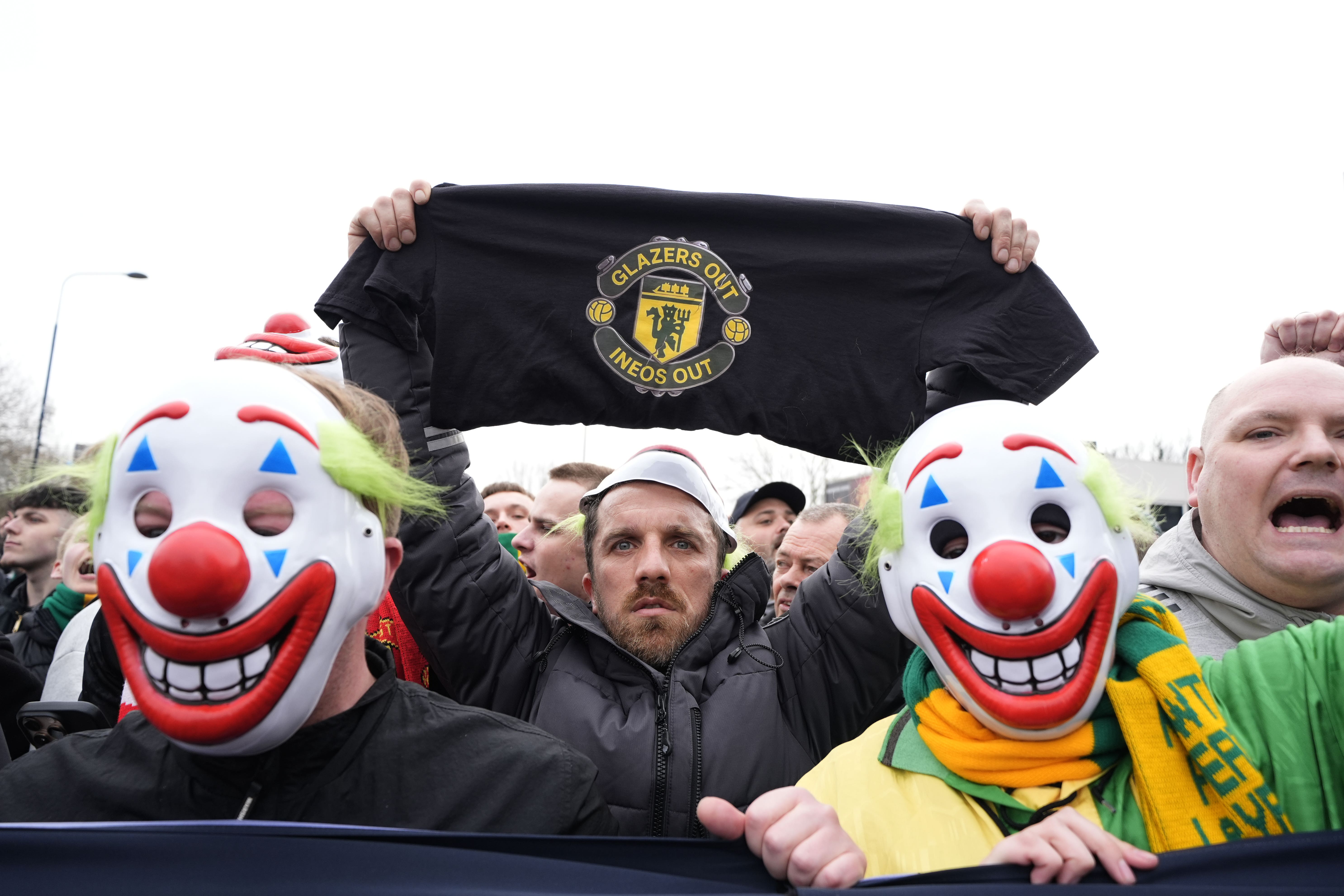 <p>Manchester United fans wore clown masks holding banners during the pre-match protest (Peter Byrne/PA)</p>