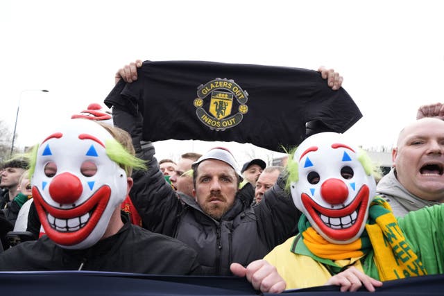<p>Manchester United fans wore clown masks holding banners during the pre-match protest (Peter Byrne/PA)</p>