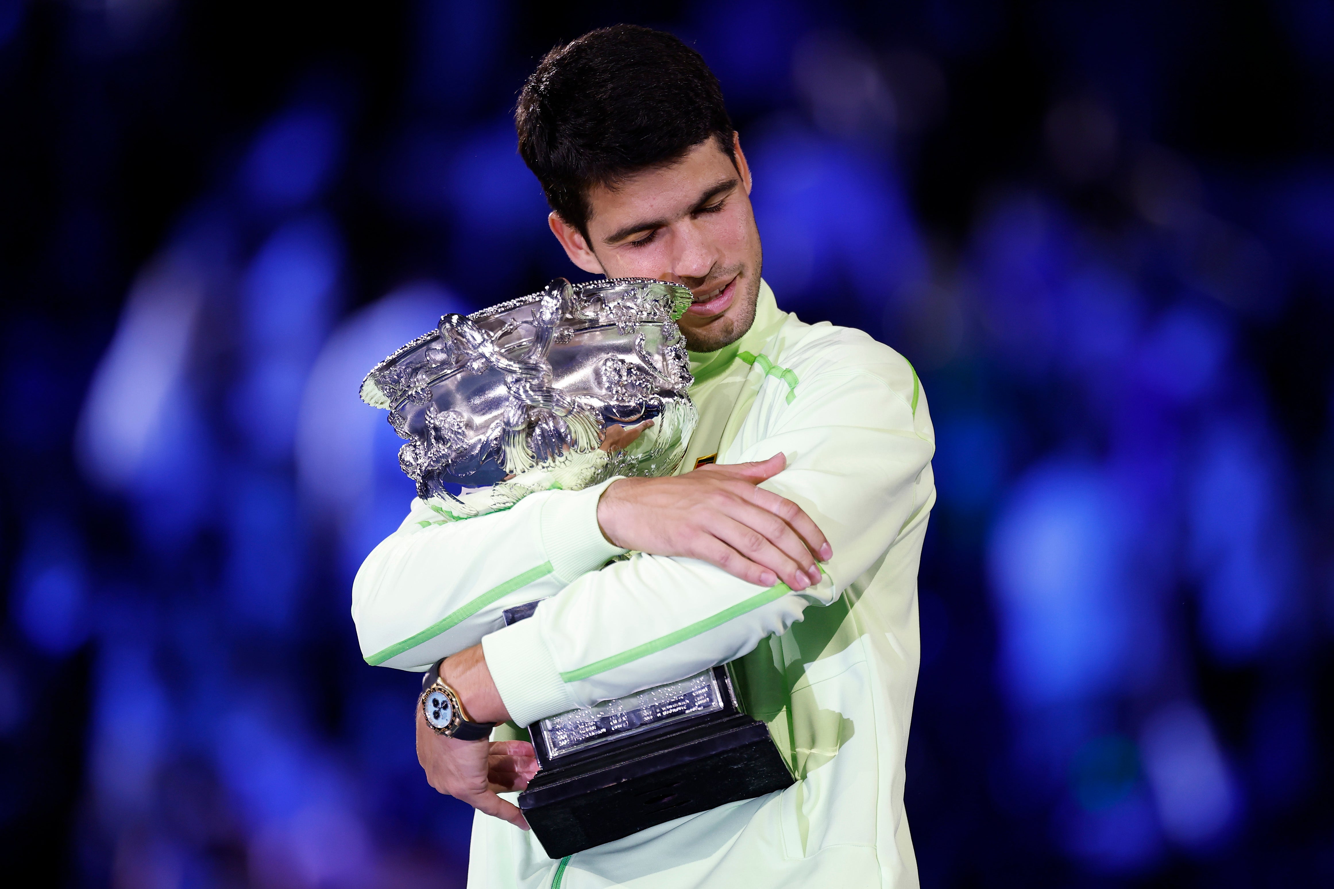 <p>Carlos Alcaraz hugs the Norman Brookes Challenge Cup after completing the career grand slam at the Australian Open</p>