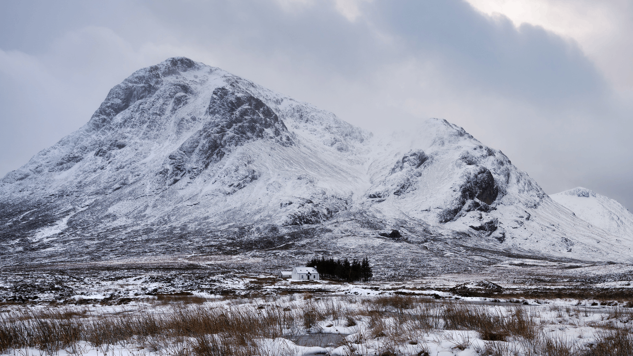Snow-tipped peaks, rust-coloured moorland and small lochs create a rugged backdrop