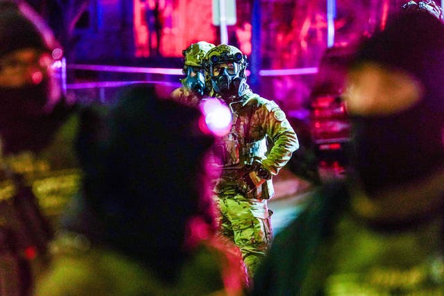 <p>Federal agents stand guard as community members protest after federal law enforcement agents were involved in a shooting incident on January 14, 2026</p>