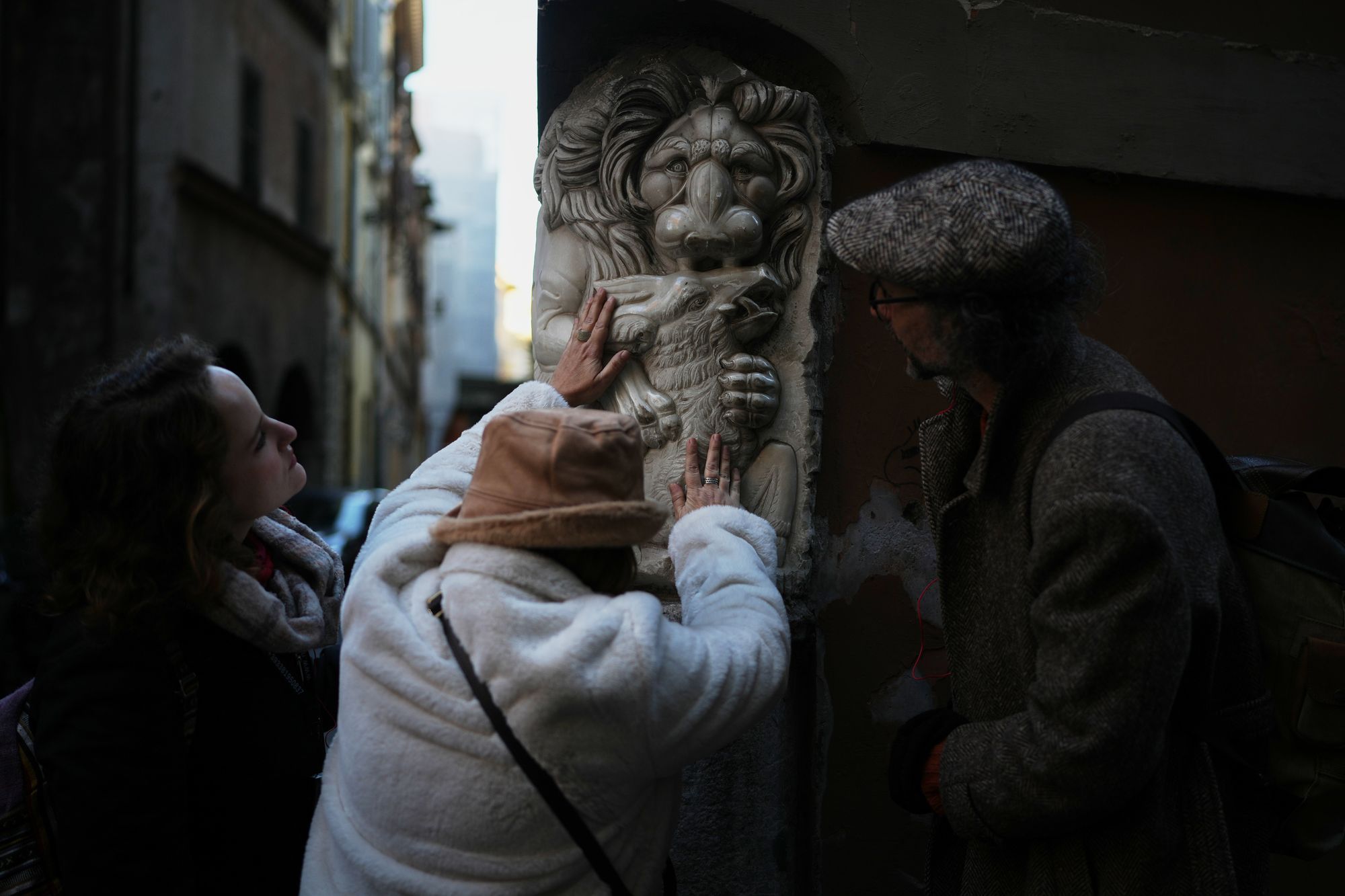 <p>Francesca Inglese, who is blind, touches a marble relief on the corner of a building during an inclusive art tour in downtown Rome</p>