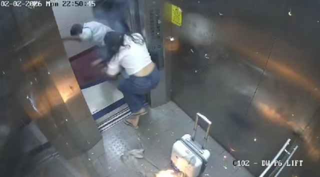 <p>Screengrab from CCTV footage shows two people rushing out of an elevator after gas-filled balloons catch fire </p>