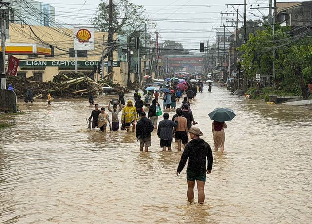 <p>People wade through floodwaters brought by Tropical Storm Penha in Iligan, Lanao del Norte, Philippines</p>