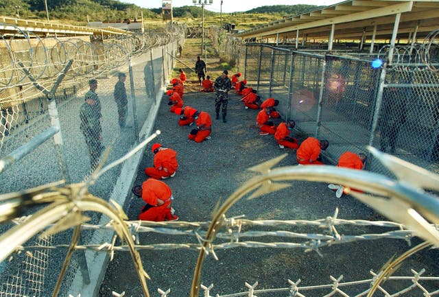 <p>Al-Qaeda and Taliban detainees sit in a holding area under the surveillance of US military police at Camp X-Ray at Naval Base Guantanamo Bay, Cuba.</p>
