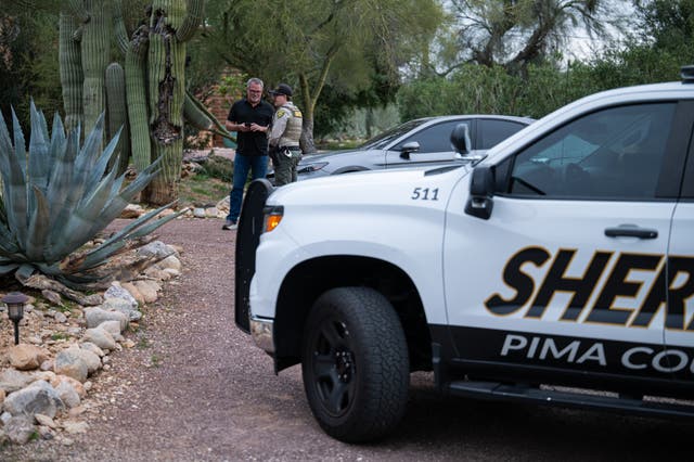 <p>A Pima County Sheriff's deputy talks with a private security guard at Nancy Guthrie's home</p>
