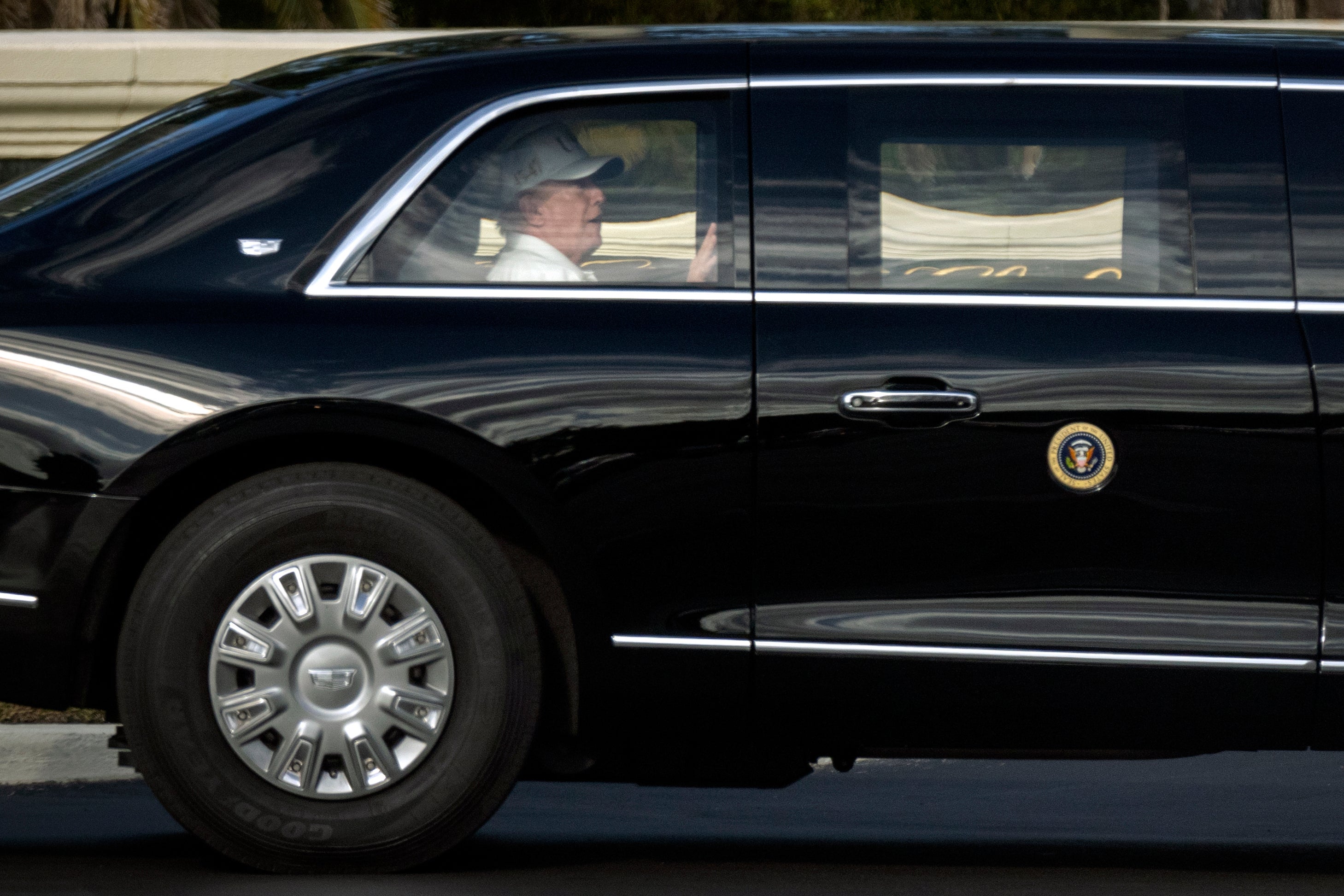<p>President Donald Trump rides in his limousine as he leaves the Trump International Golf Club</p>