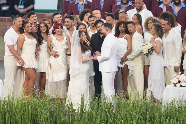 <p>Un oficiante sonriente declaró a la pareja casada, quienes, vestidos de blanco, compartieron un beso rodeados de bailarines y músicos.</p>