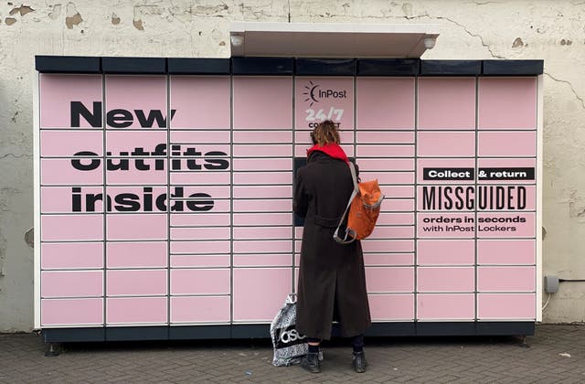 <p>A woman stands at an InPost locker in Hackney, east London</p>