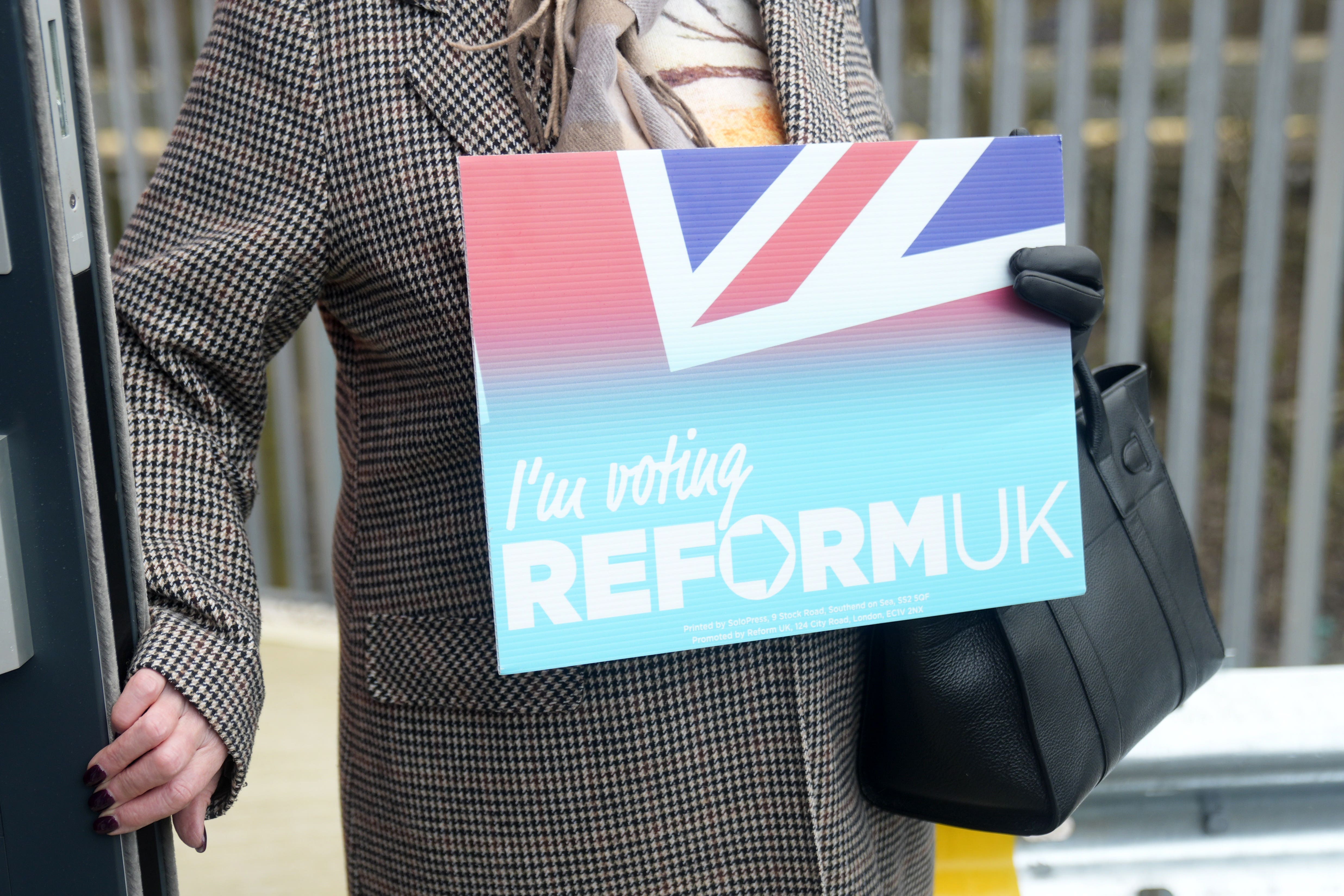 A Reform UK supporter holding a placard at the party’s Gorton and Denton by-election headquarters in Denton. (Danny Lawson/PA)