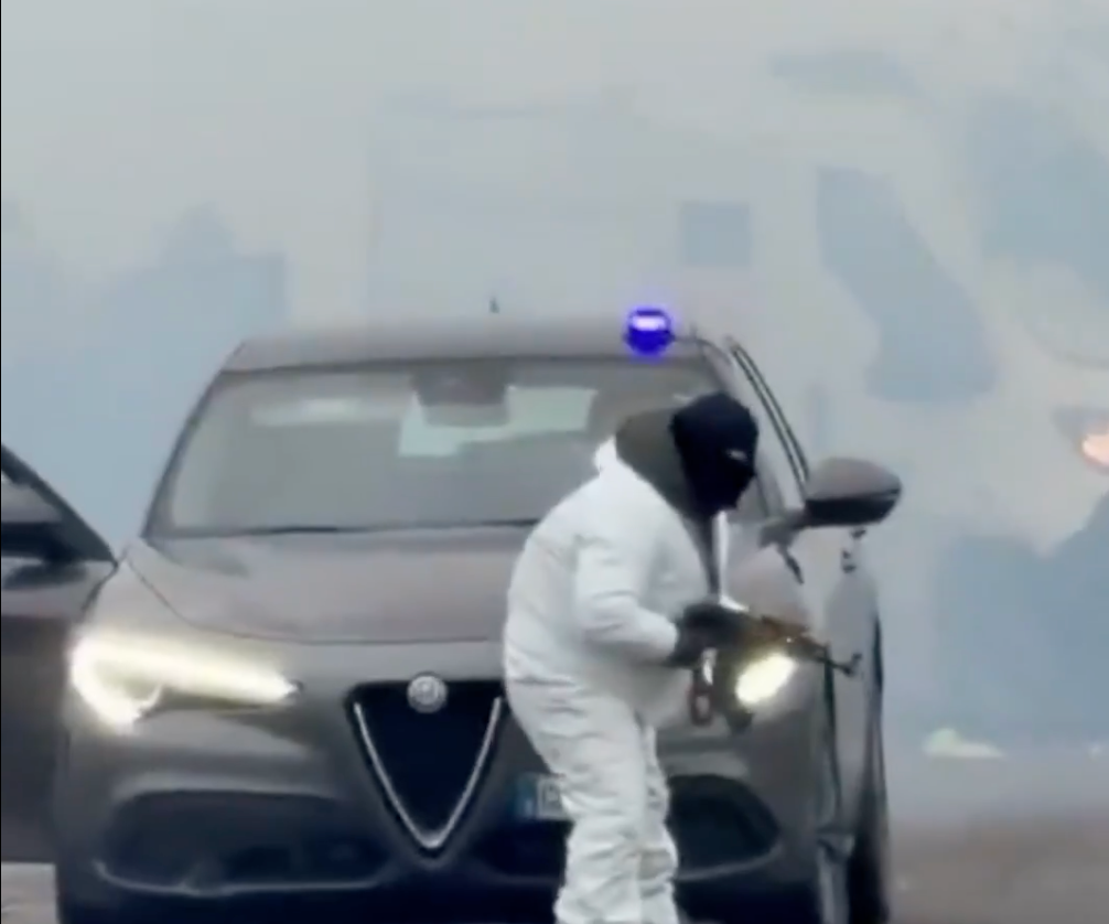 A man in white overalls kept watch with a gun while his accomplices appear to unload the van during the robbery