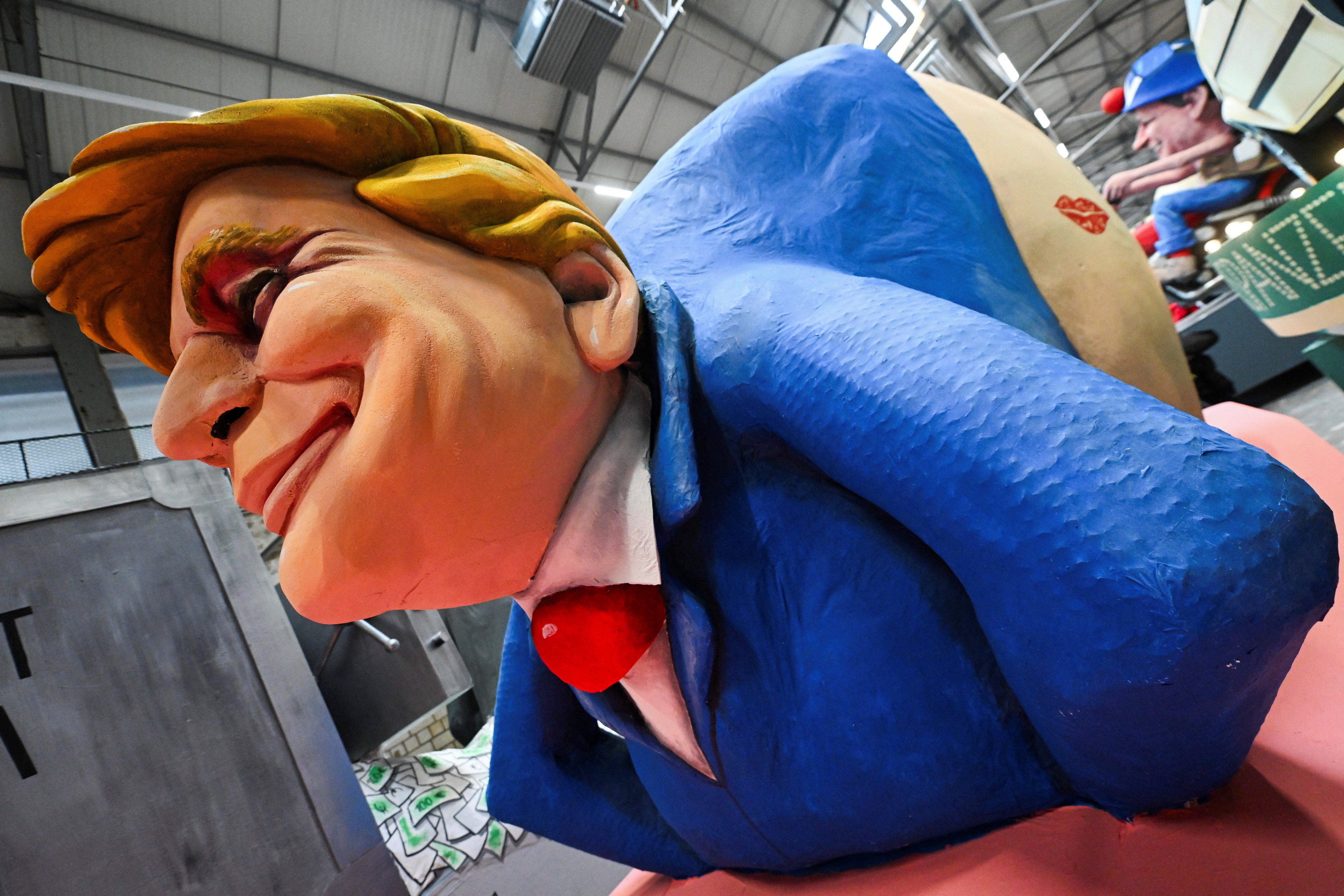 <p>A sign points to Trump’s bottom alongside the words ‘kiss here!’</p>