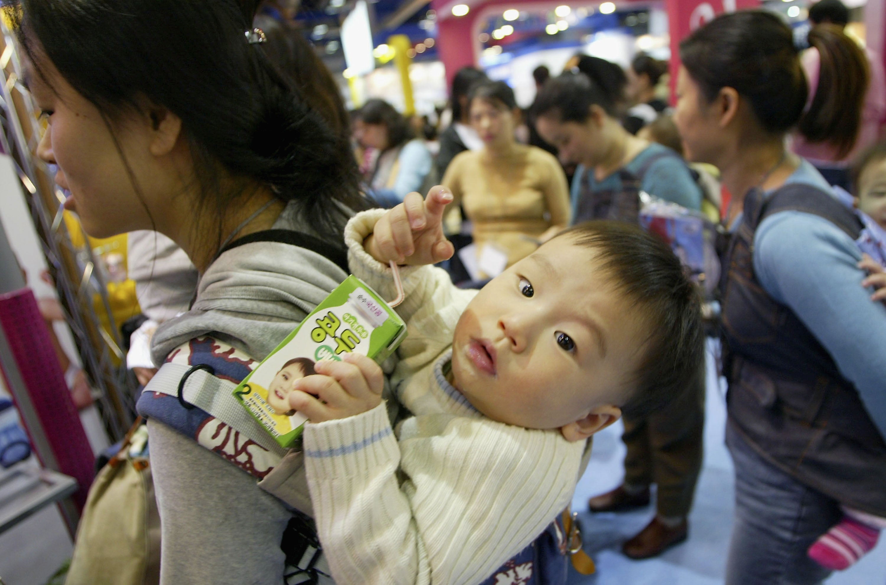 <p>A mothers carry her baby at a Pregnancy and Maternity exhibition on 17 February, 2005 in Seoul</p>