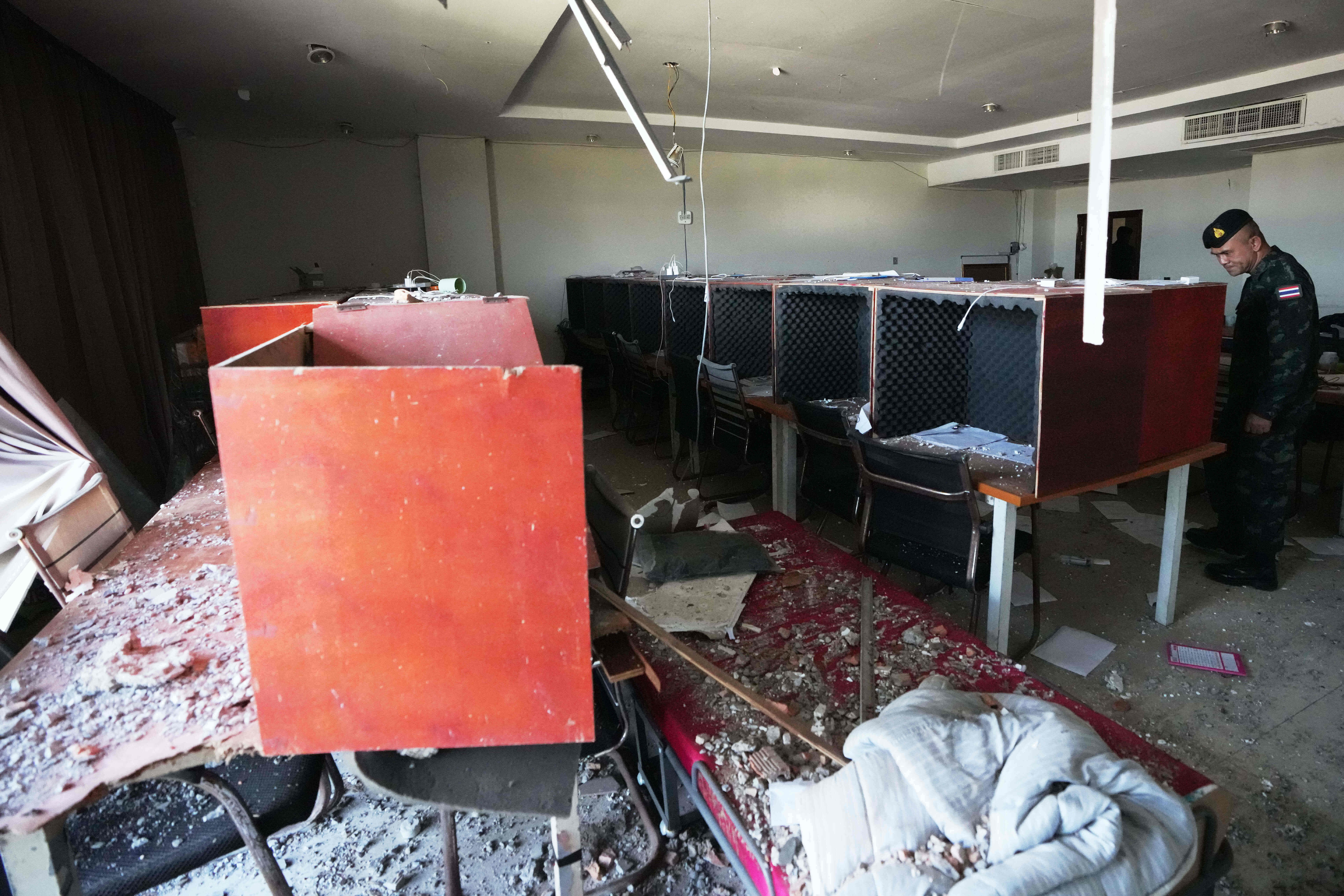 Тајландски војник прегледа радну станицу са дрвеним телефонским говорницама обложеним пеном за звучну изолацију, унутар комплекса за преваре у О'Смацху, Камбоџа