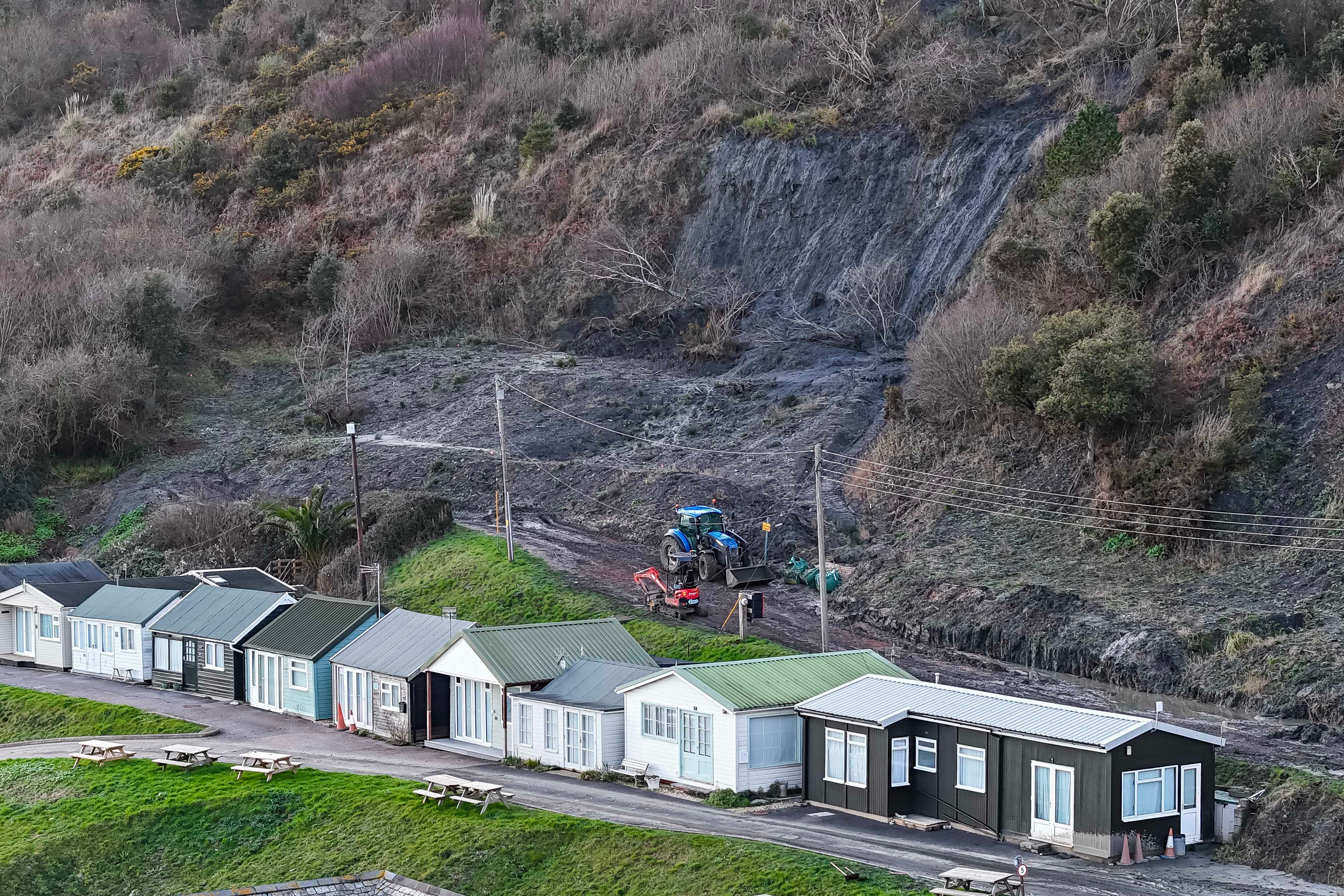 Further up the coast clear up is underway after a small landslip on the clay cliffs behind chalets at Monmouth Beach at Lyme Regis in Dorset