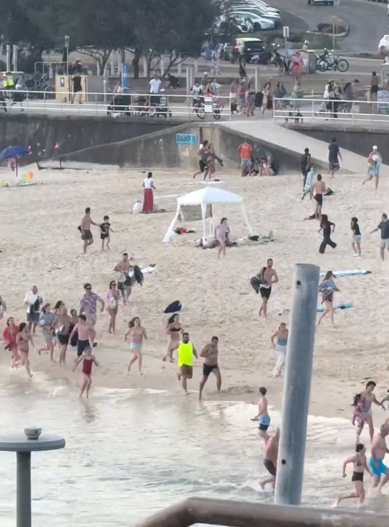 People run on the beach during a shooting incident on a Jewish holiday celebration at Bondi Beach in Sydney