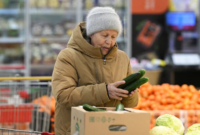 <p>A customer selects cucumbers at a supermarket in Omsk, Russia</p>