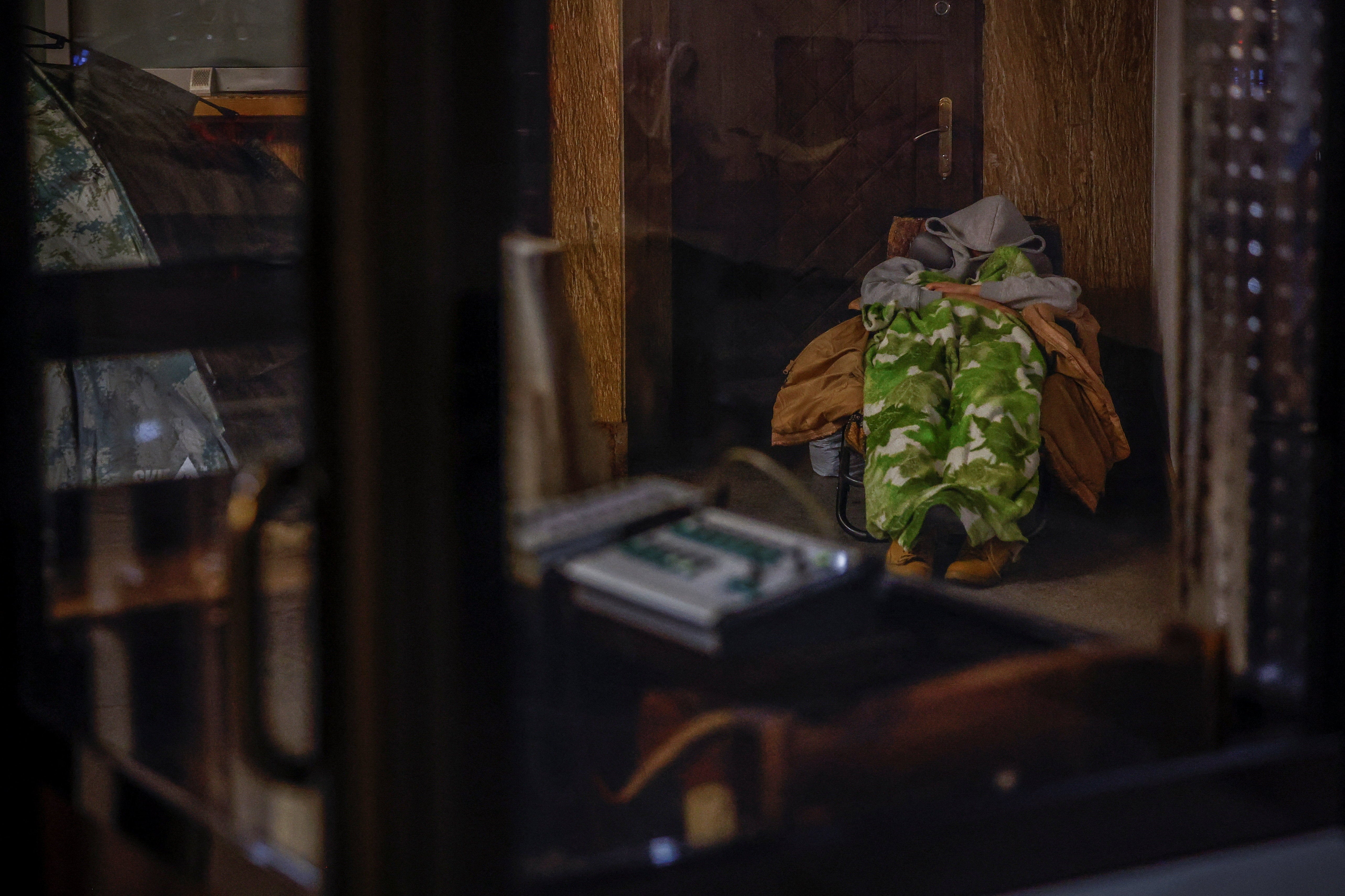 A person tries to sleep while taking shelter inside a metro station during an air raid alert in Kyiv