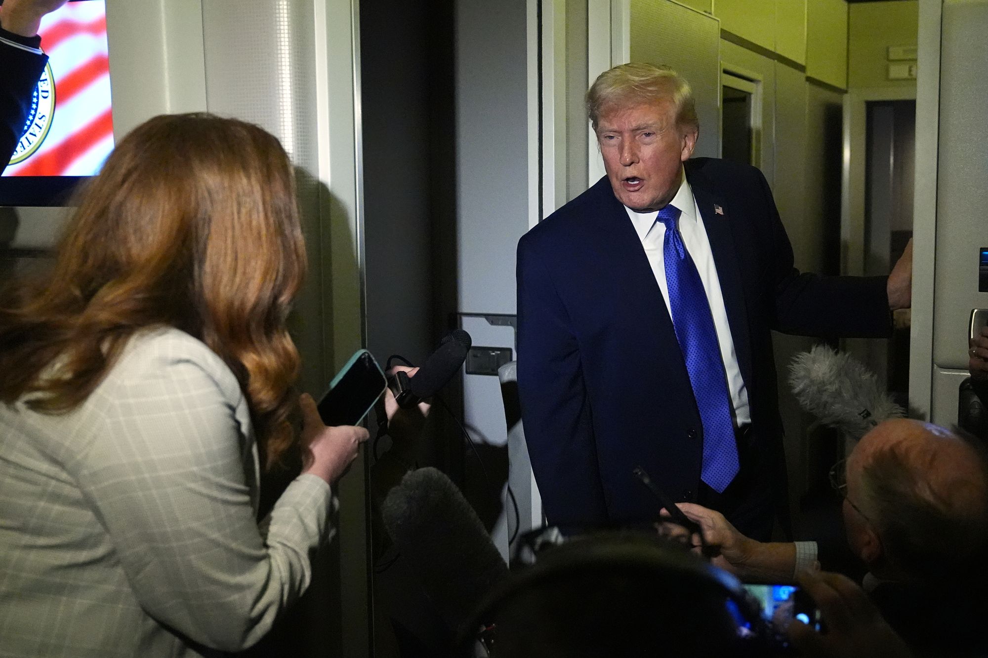 President Donald Trump speaks with reporters aboard Air Force One