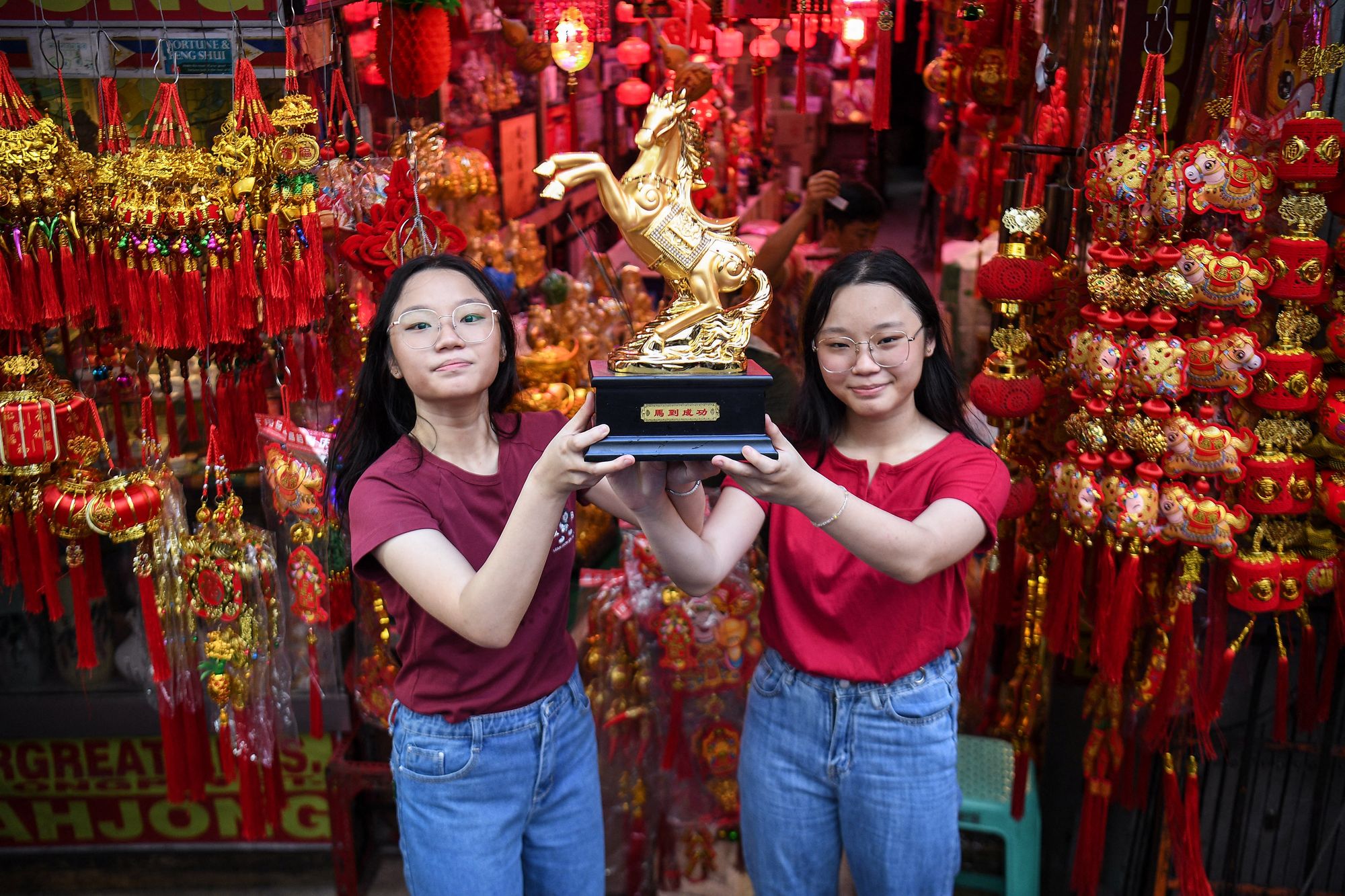 Young girls display a horse figurine in front of their store during the first day of the Lunar New Year of the Horse in the Chinatown district of Manila.