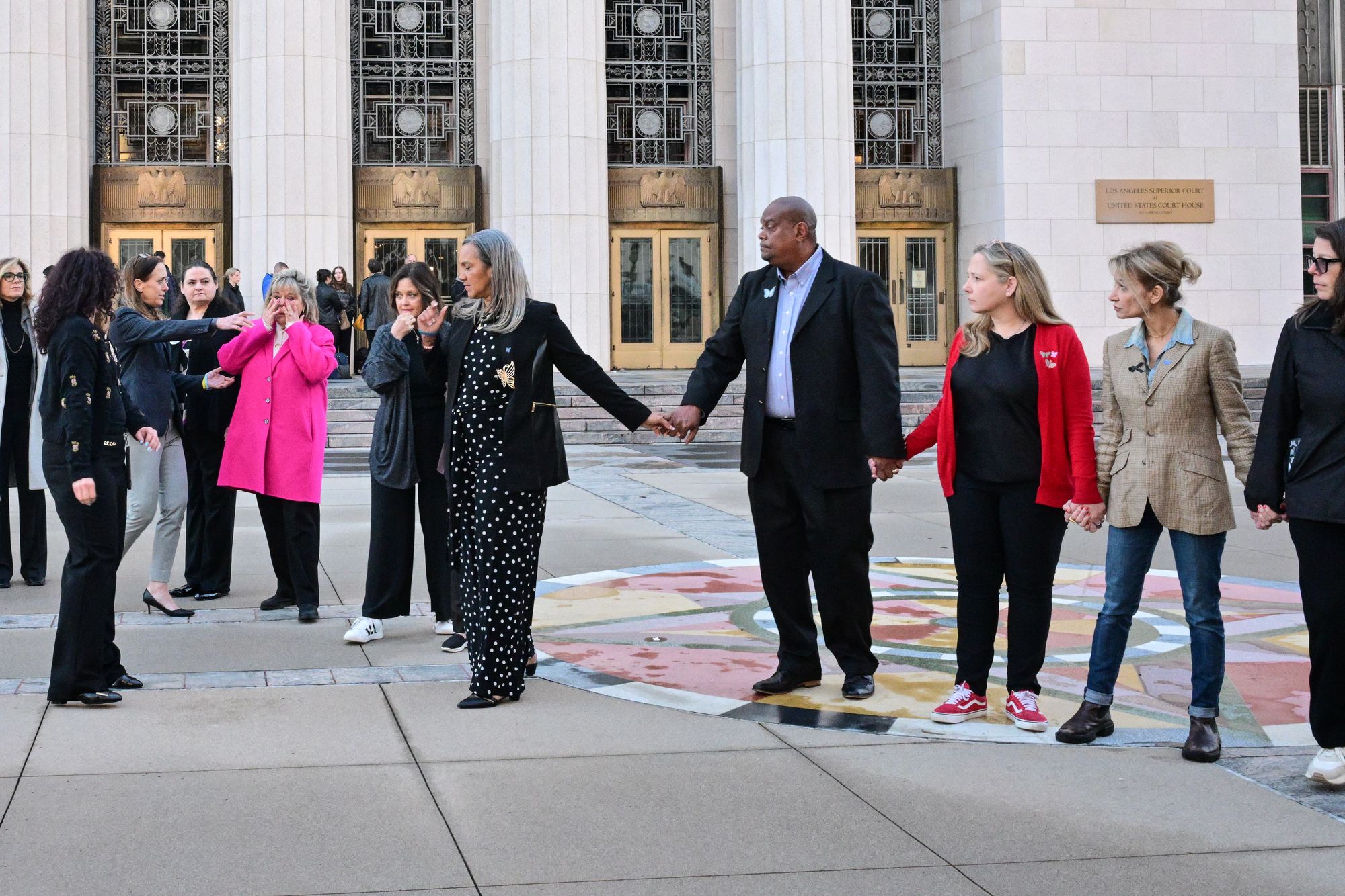 Parents and family members, some of whom are plaintiffs in the case, hold hands before entering the Los Angeles Superior Court on Wednesday