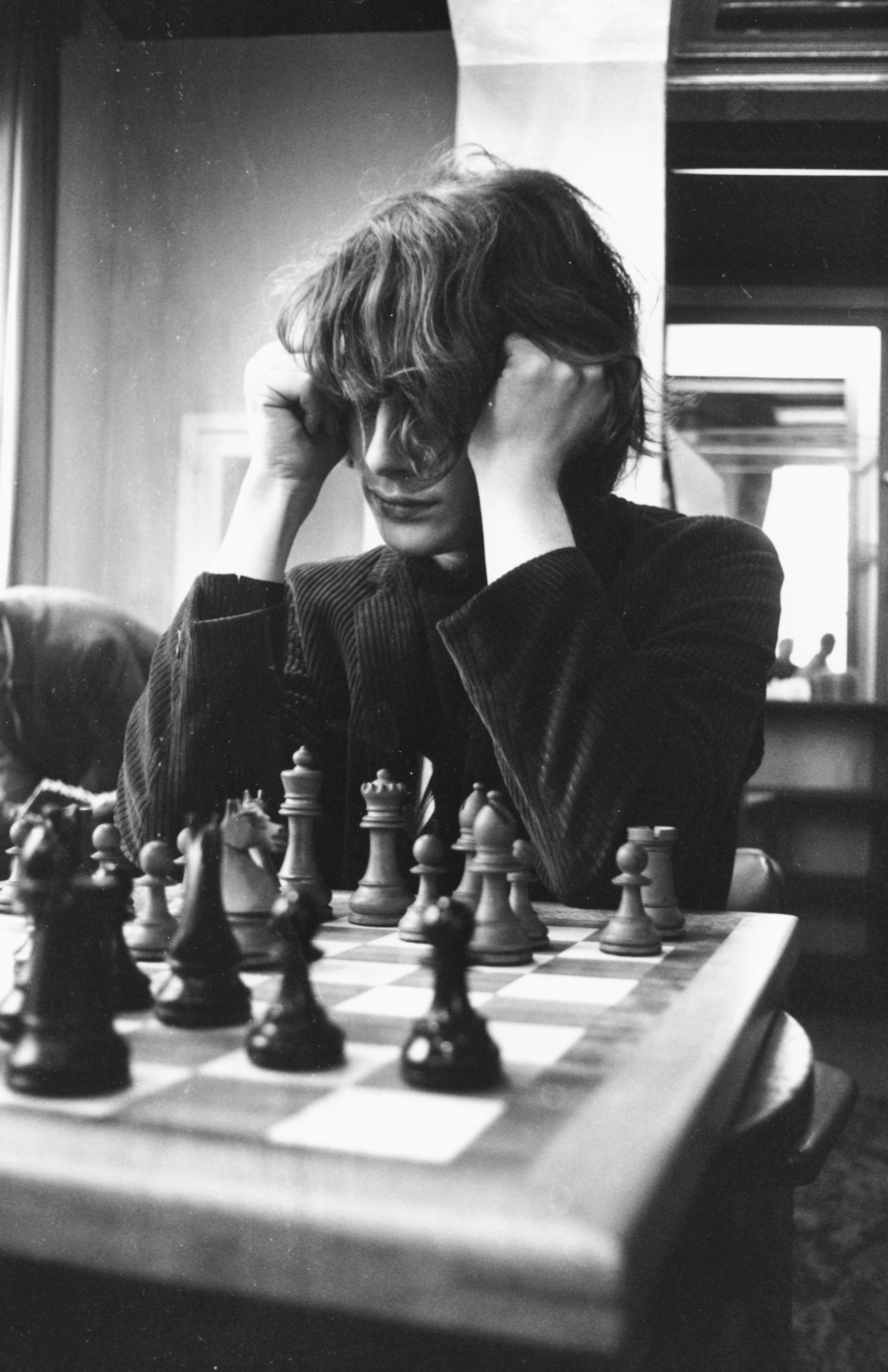 Professional chess player Jan Timman studying a chess board through his long hair during a match at the International Chess Congress in Hastings, 29 December, 1969