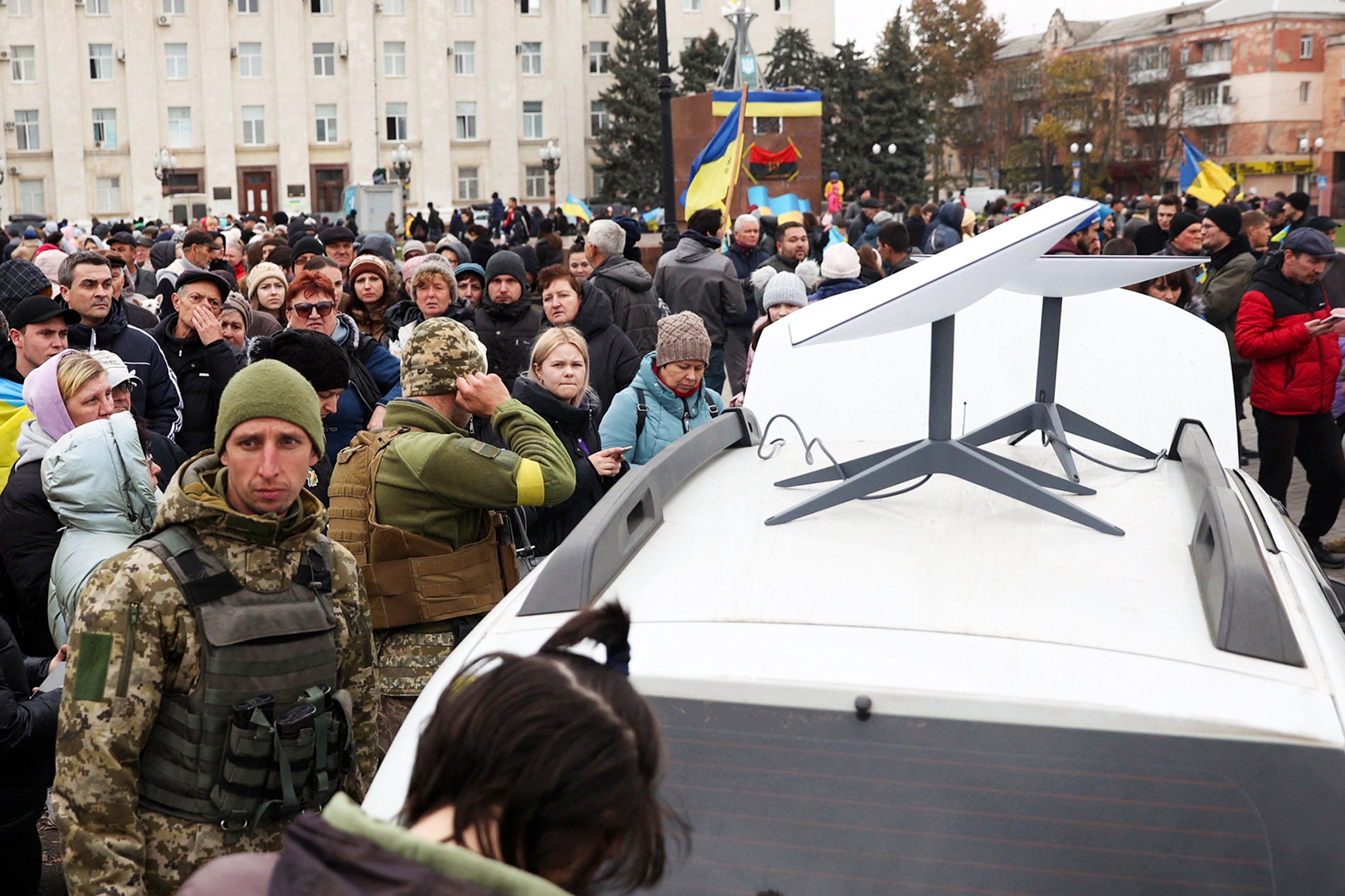 Ukrainians use their mobile phones standing near a Starlink satellite-based broadband station in Kherson