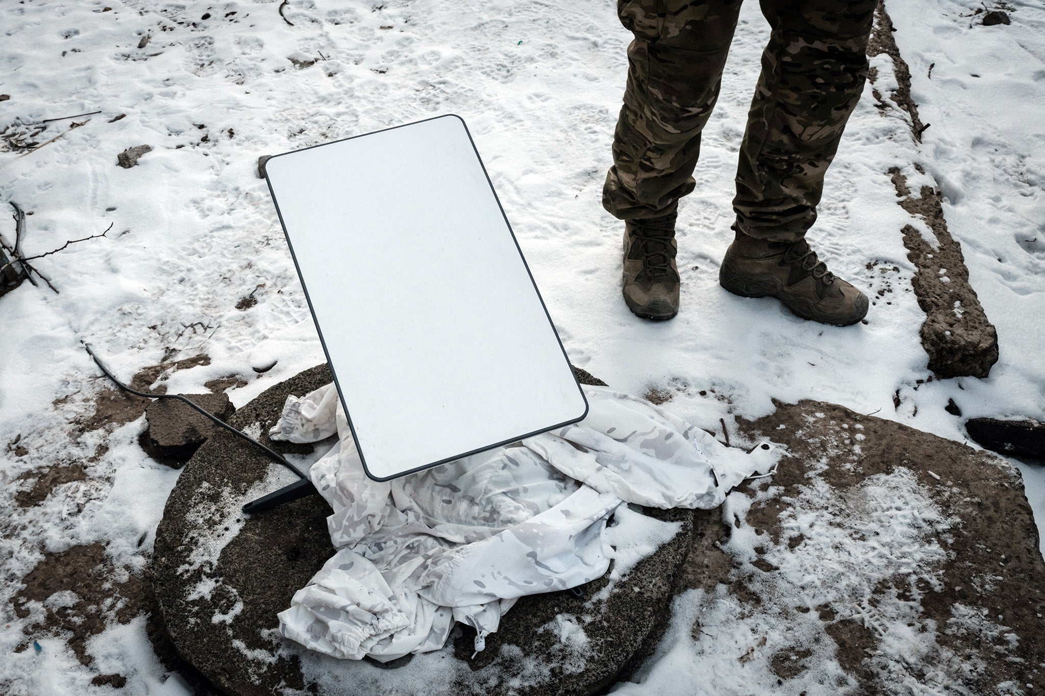 A Ukrainian serviceman stands next to the antenna of the Starlink satellite-based broadband system in Bakhmut