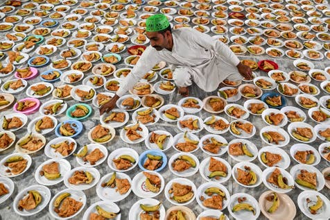 <p>A volunteer prepares the plates of Iftar food on the first day of the Islamic holy month of Ramadan at the Data Darbar shrine in Lahore </p>
