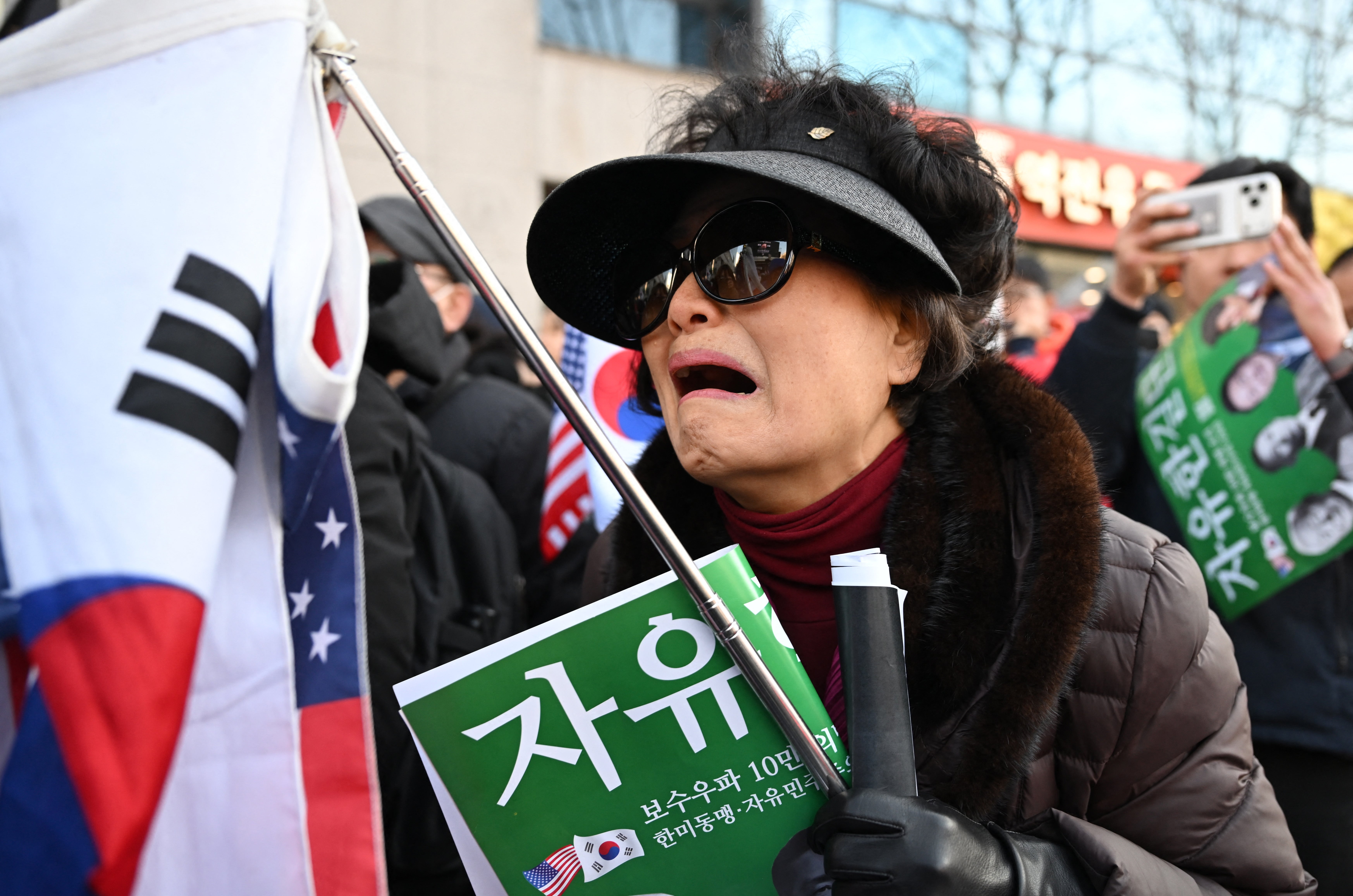 Supporters of South Korea's impeached former president Yoon Suk Yeol react as they watch a live stream of Yoon's trial on his insurrection charges near the Seoul Central District Court in Seoul