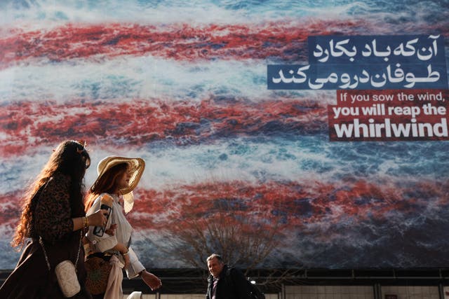 <p>Iranian women walk past an anti-U.S. billboard in Tehran</p>