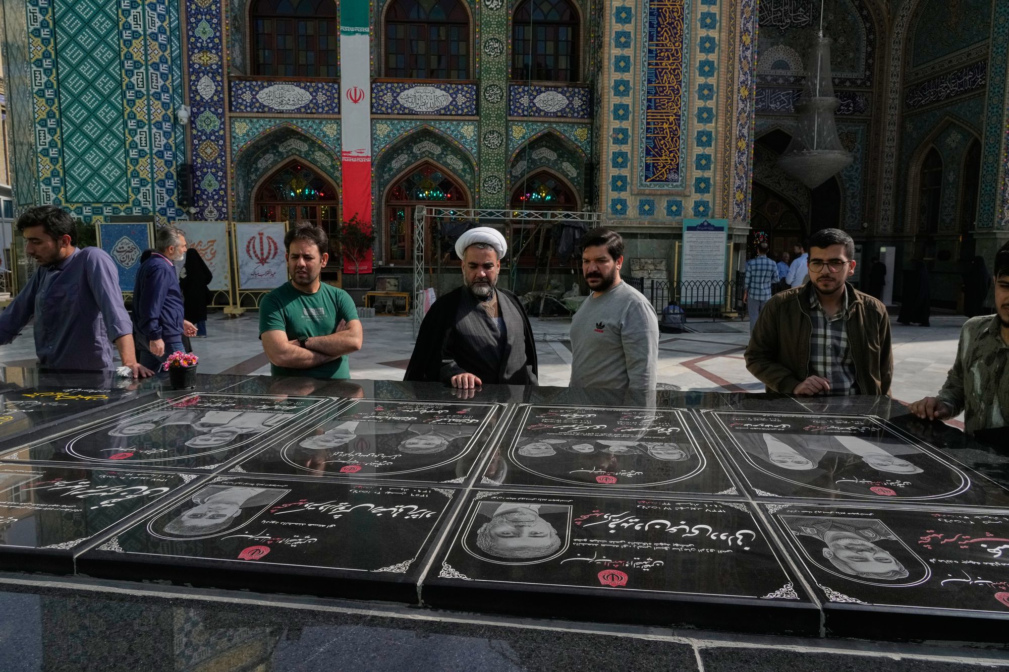 A cleric and other people pray at the graves of Iranian nuclear scientists, their families and a Revolutionary Guard commander who mainly killed in Israeli strikes in June 2025, at the shrine of Saint Saleh during the Muslim holy fasting month of Ramadan in northern Tehran, Iran