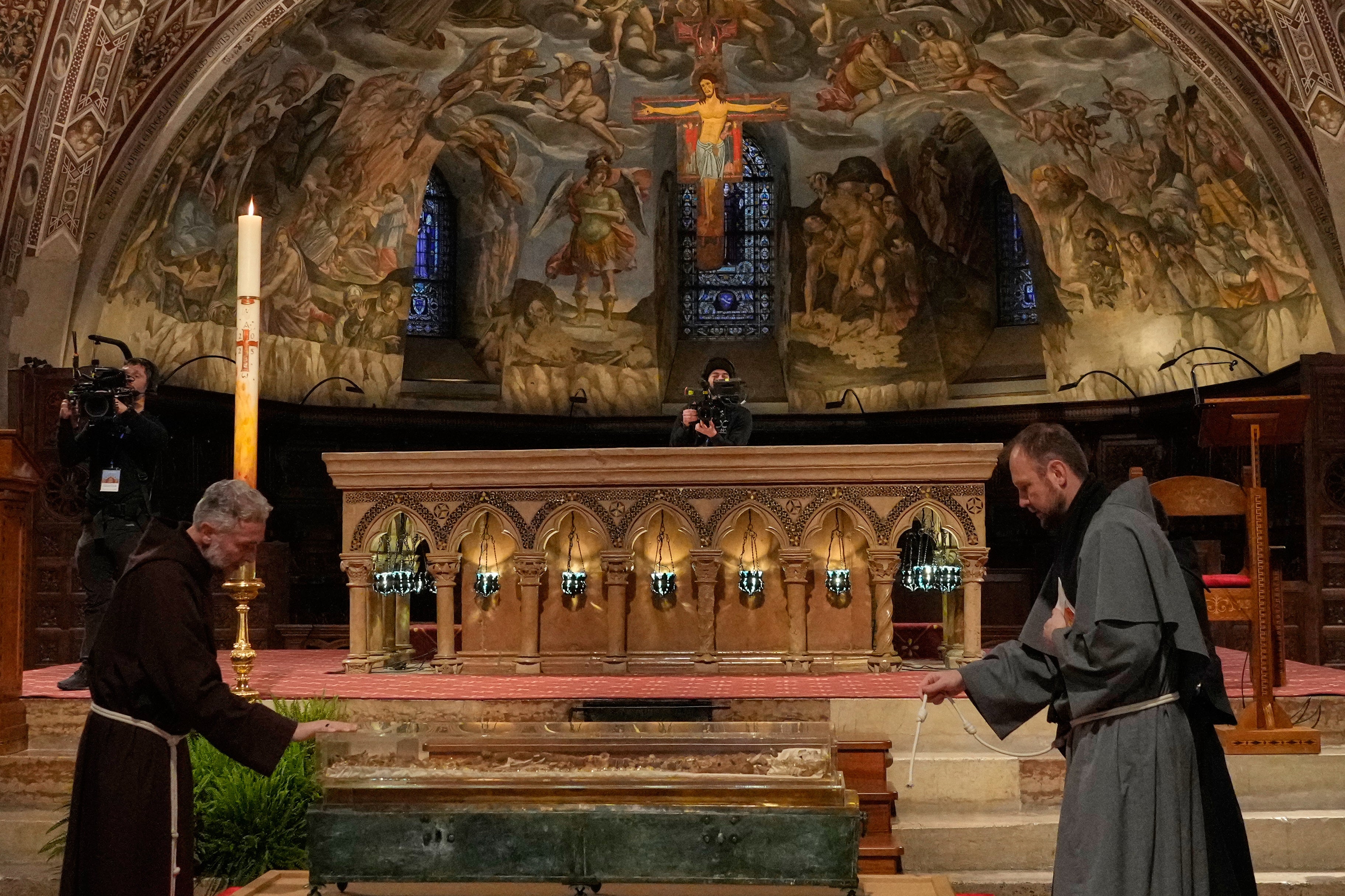 Friars pray before the remains of Francis of Assisi inside the Basilica of St. Francis of Assisi