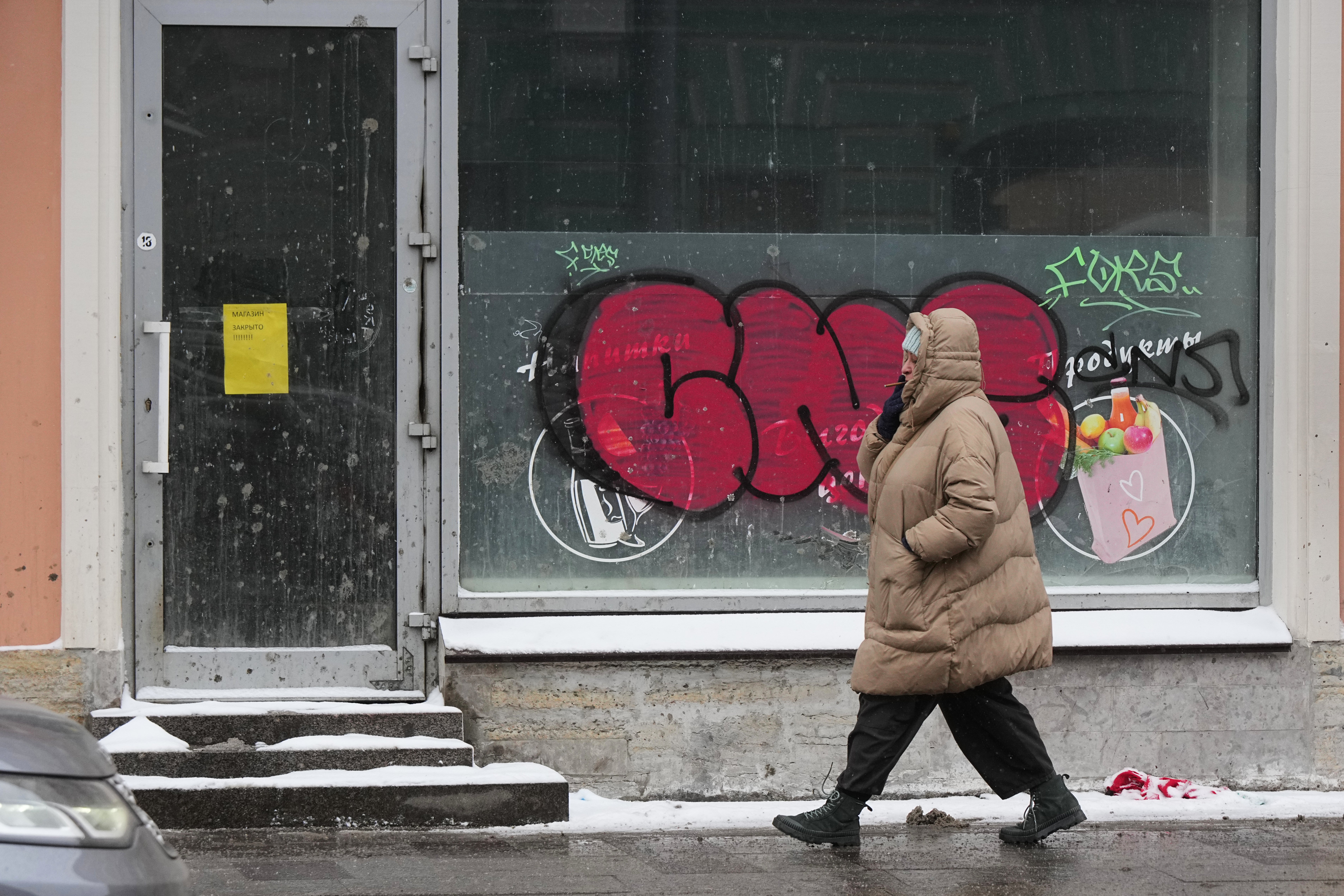 A woman walks past a closed grocery shop in St. Petersburg, Russia