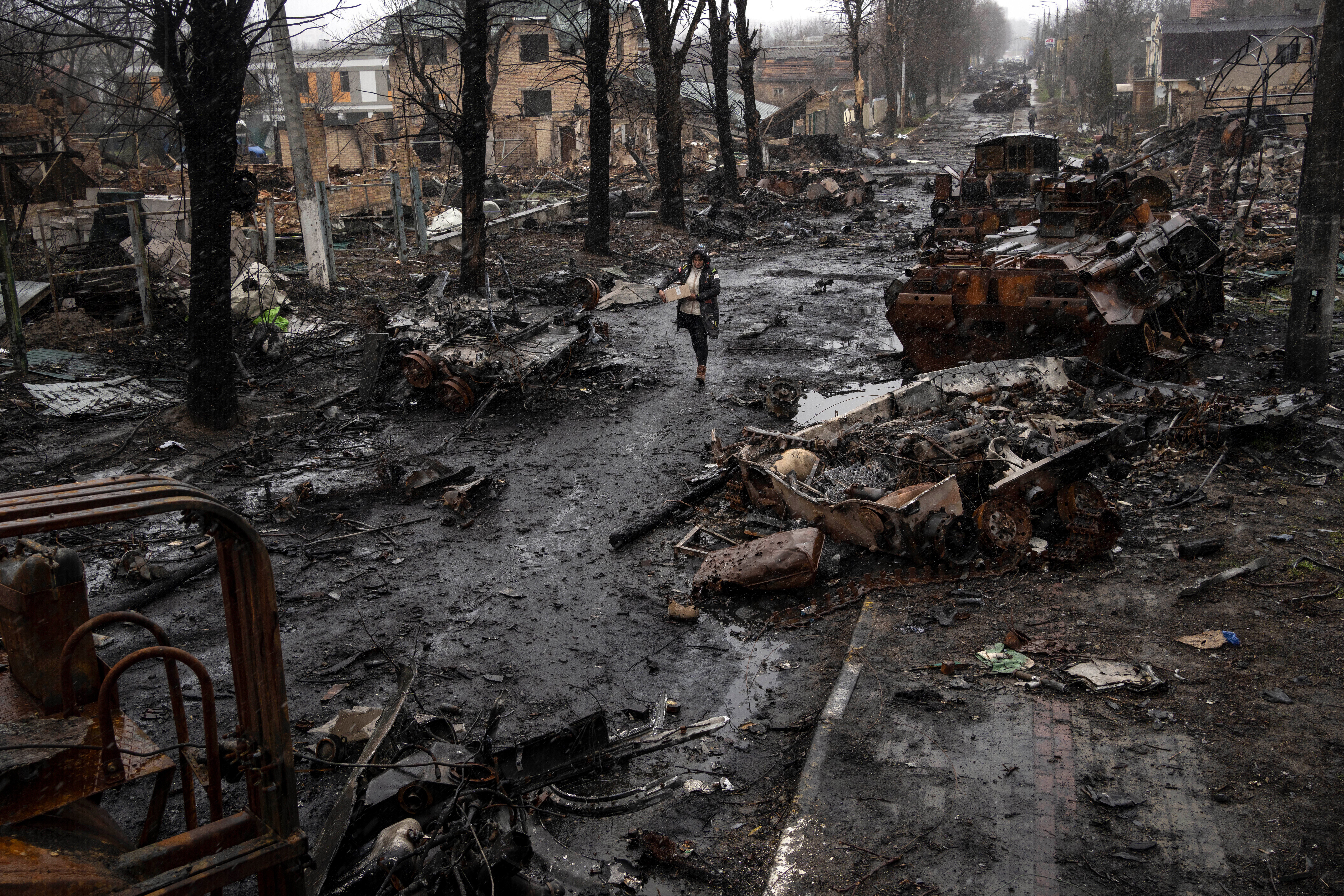 A woman navigates a debris-filled street where destroyed Russian military vehicles stand in Bucha on the outskirts of Kyiv.