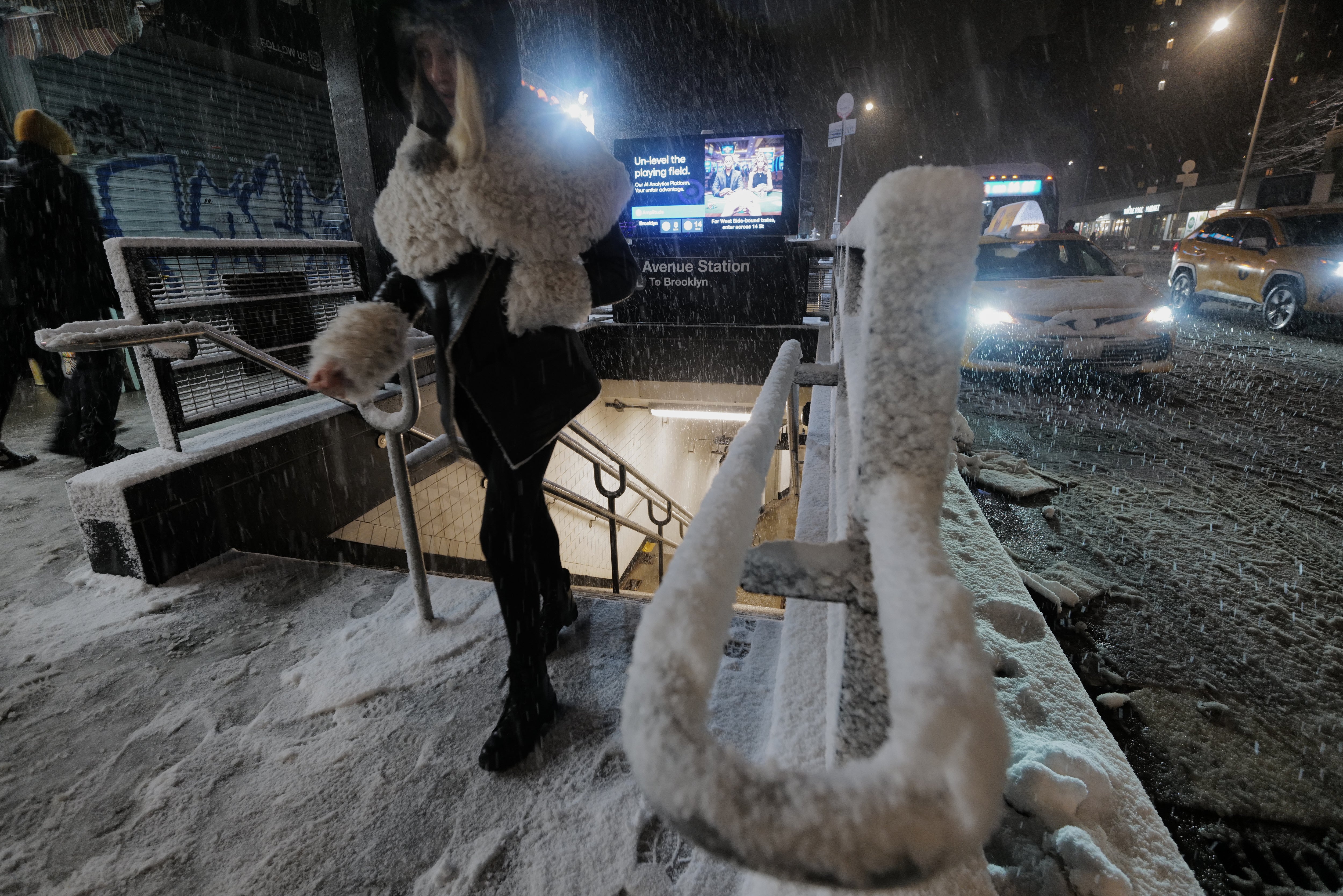 <p>A passenger exits a subway station as snow falls in Alphabet City, New York</p>