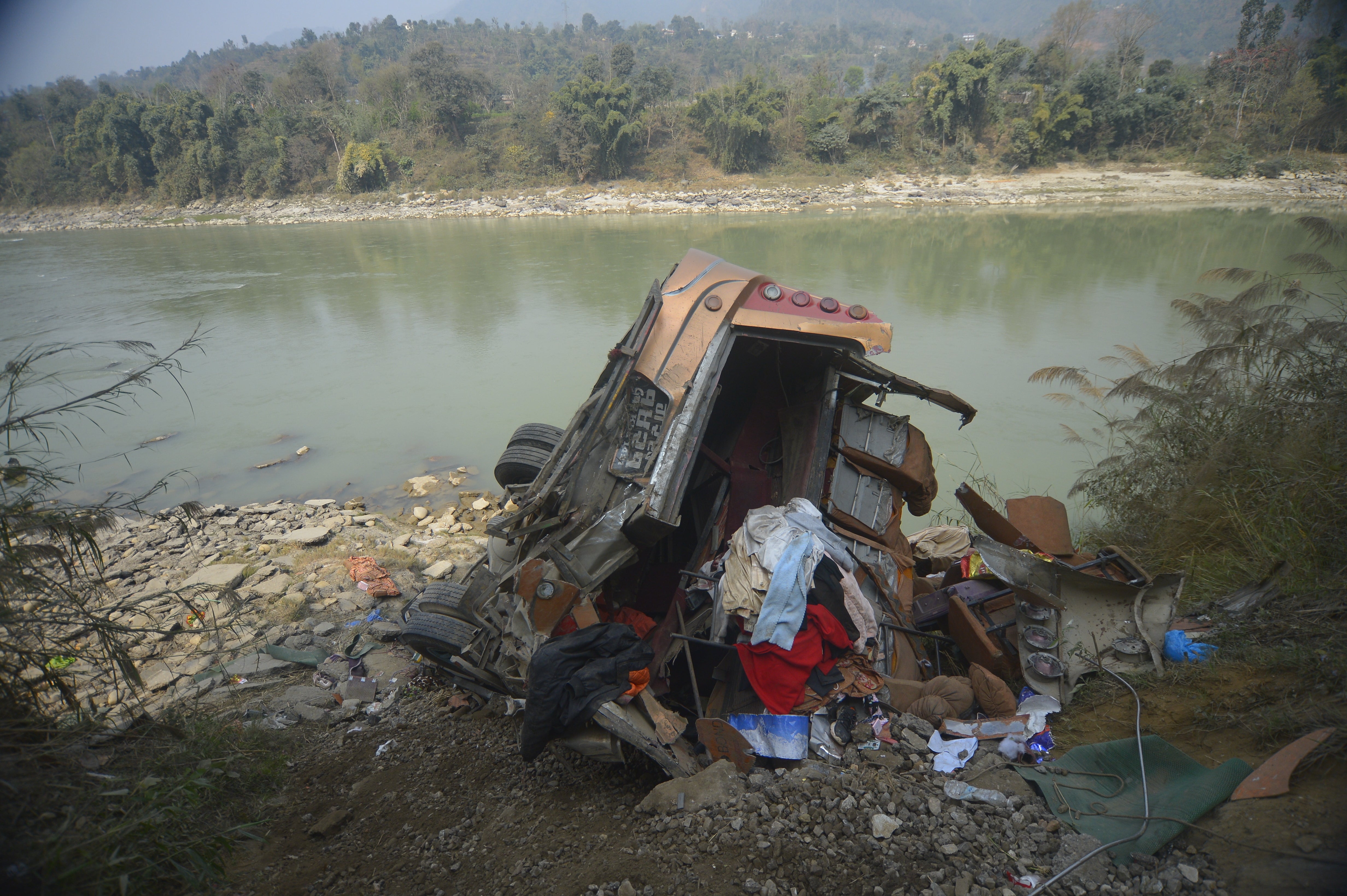 The wreckage of a bus is seen on the bank of the Trishuli River