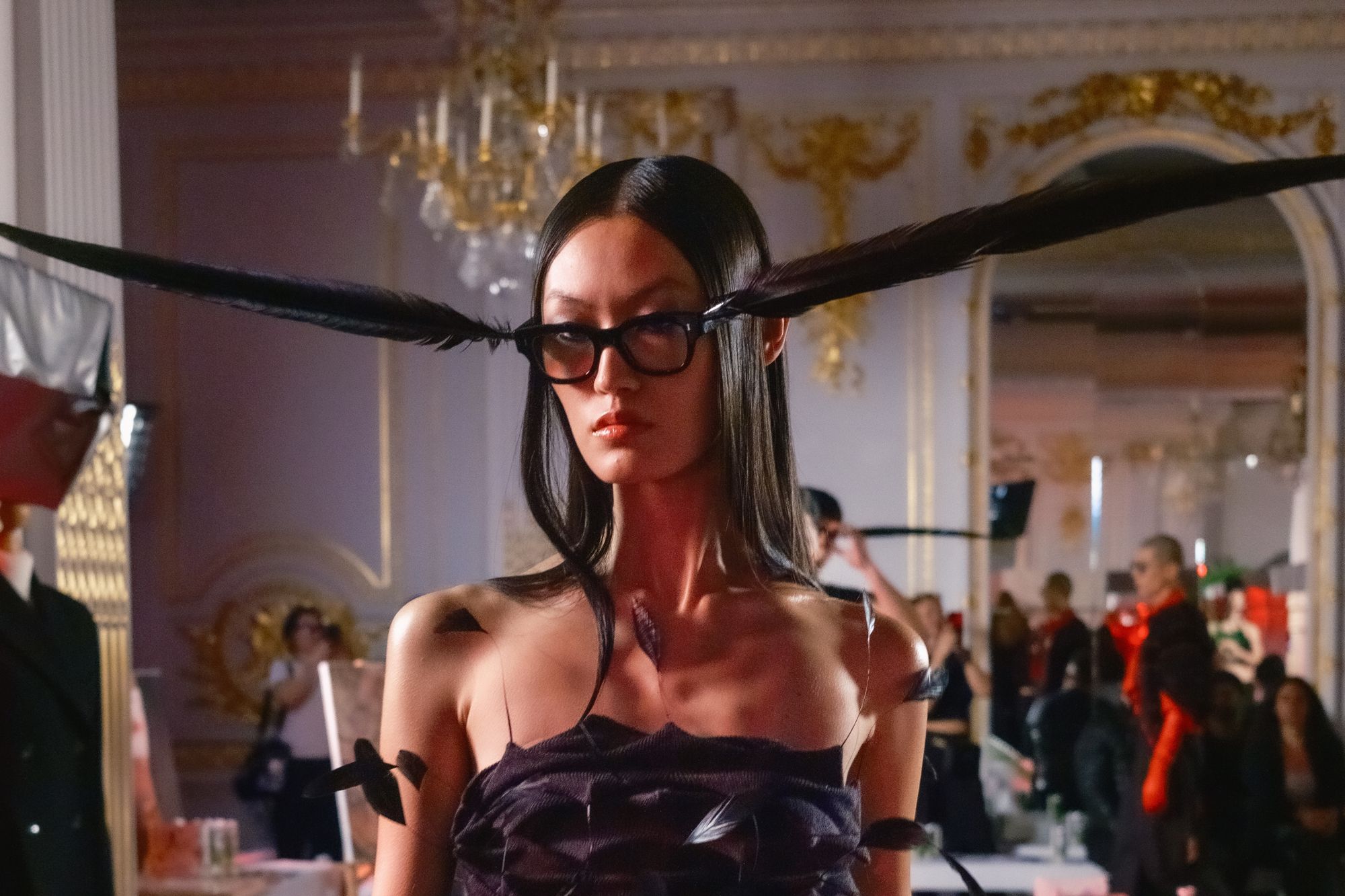 <p>A model with long straight hair and feathers on glasses at Chet Lo show</p>