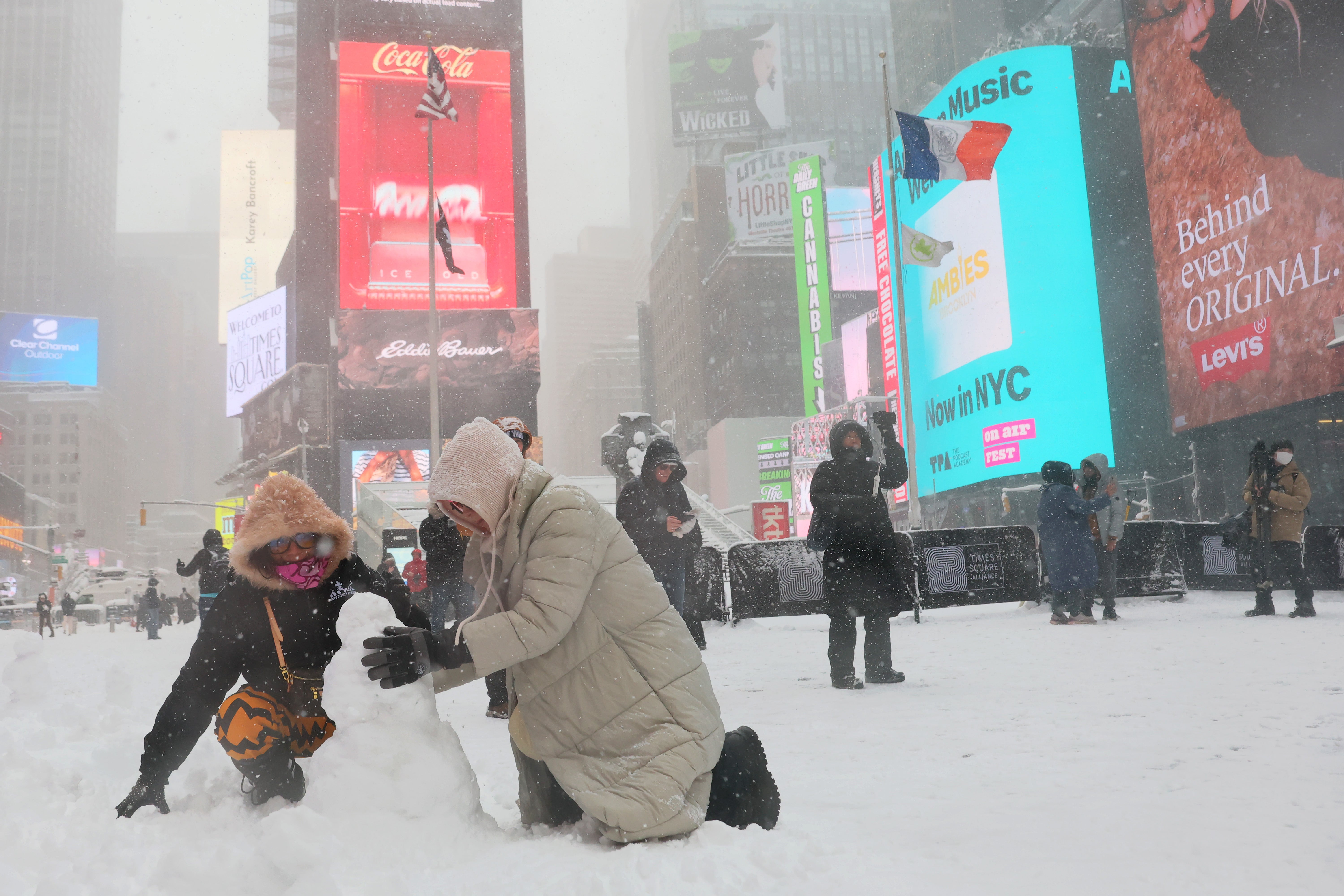 People build a snowman in Times Square amid a blizzard on February 23, 2026 in New York City