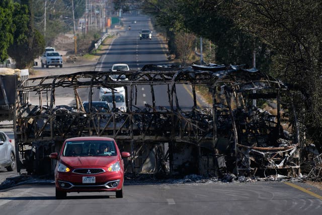 Vehicles drive past a charred bus the day after the Mexican army killed Jalisco New Generation Cartel leader Nemesio Oseguera Cervantes, known as El Mencho