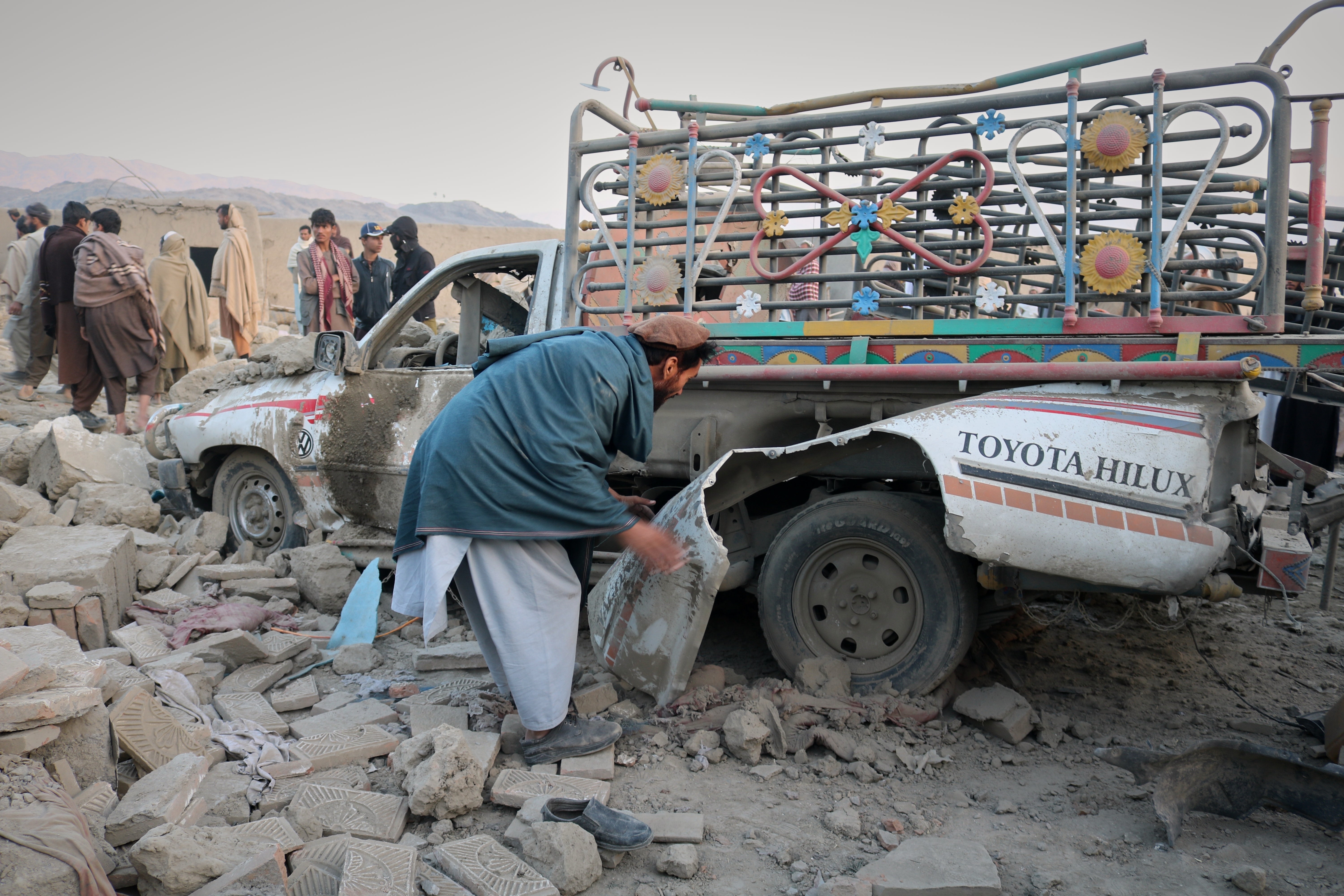 A man inspects a damaged car at the site of a cross-border Pakistani army strike in the Behsud district of Nangarhar province, Afghanistan, Sunday, Feb. 22, 2026. (AP Photo/Hedayat Shah)