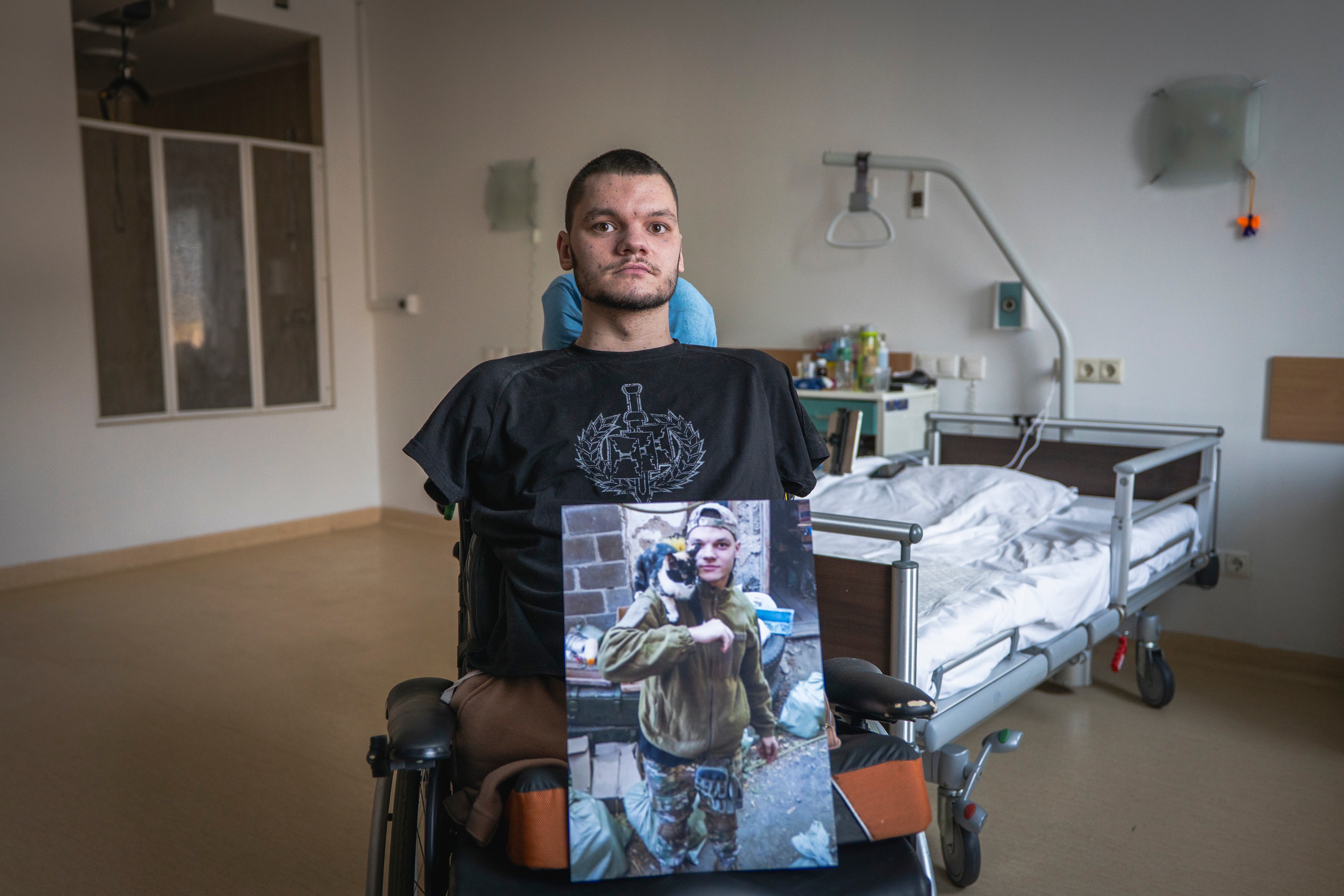 The cost of war: Ruslan Knysh, 20, a war veteran, sits in a wheelchair with a photograph of himself taken before he lost his limbs in a drone attack last year, in Kyiv, on Sunday