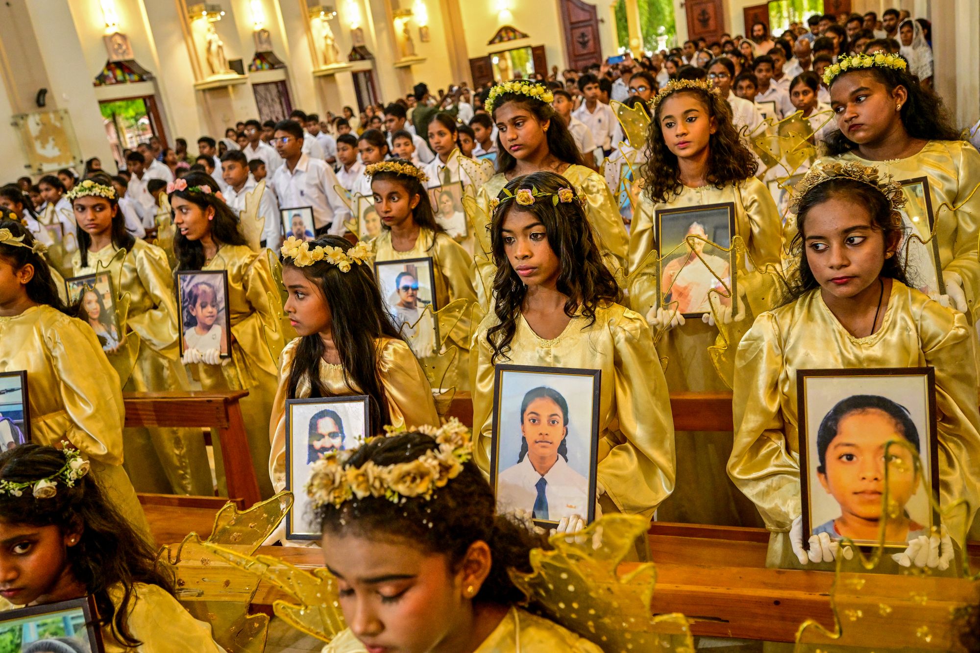 Деца са сликама жртава одају почаст шестој годишњици напада на Ускршњу недељу 2019. у цркви Светог Себастијана у Катувапитији