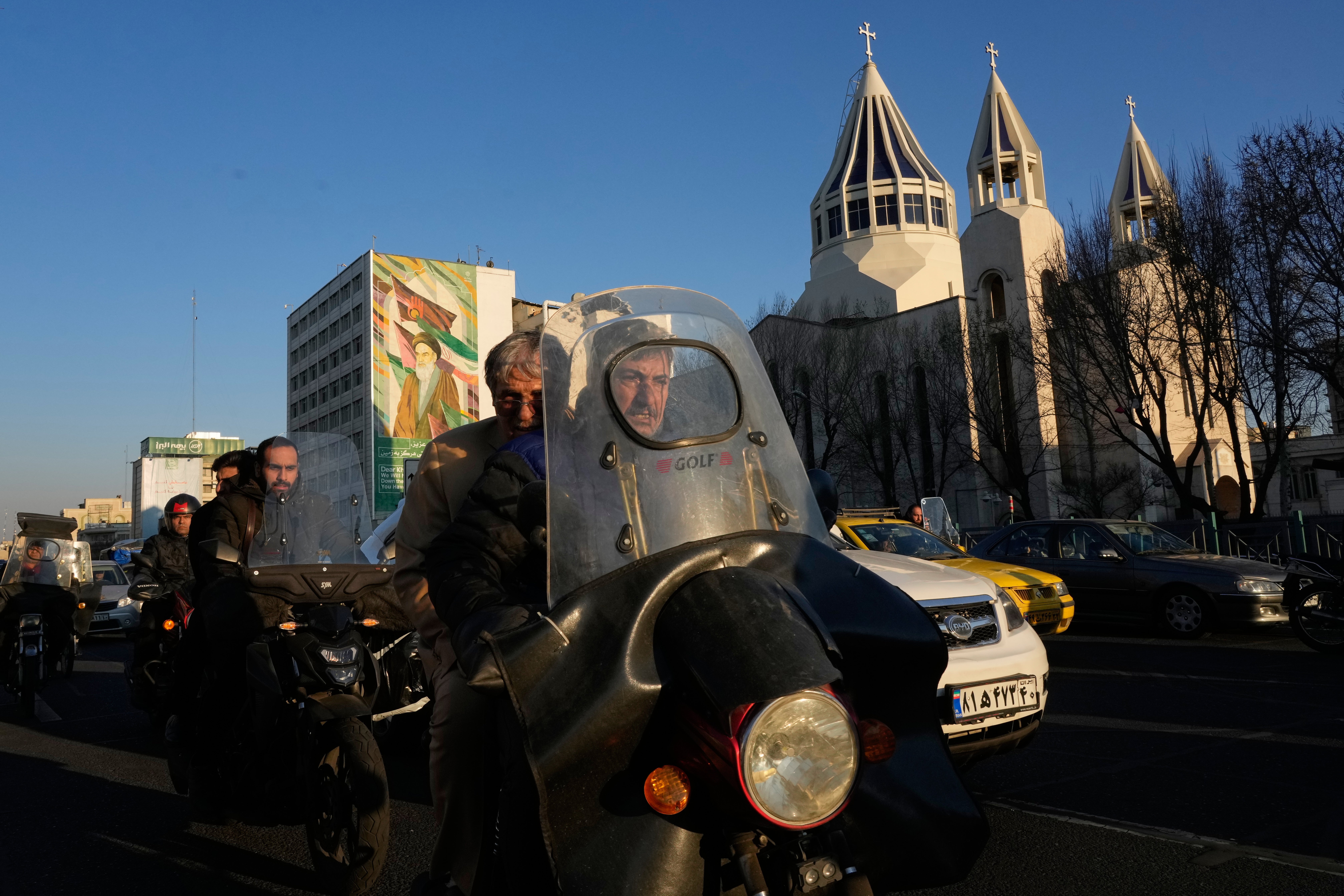 Commuters drive past Saint Sarkis church and a mural of the late Iranian revolutionary founder Ayatollah Khomeini in downtown Tehran, Iran, 25 Feb 2026. (AP Photo/Vahid Salemi)