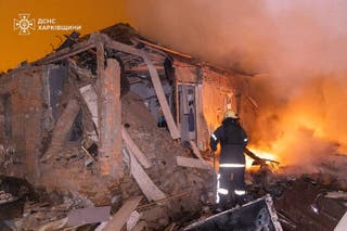 A firefighter extinguishing a fire in a damaged house following a Russian attack in Kharkiv