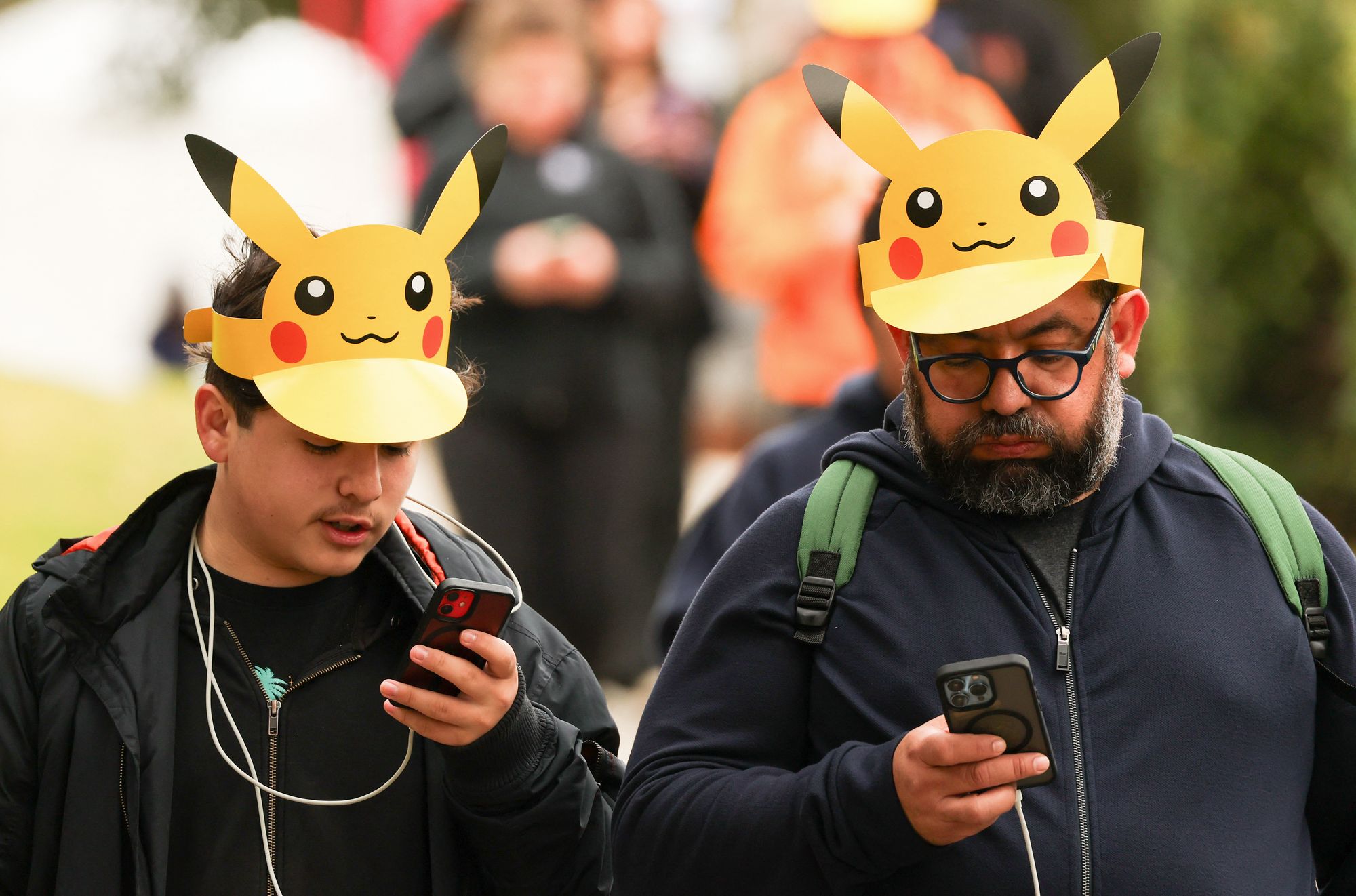 <p>Attendees wearing Pikachu hats play Pokemon GO on their smartphones during the in-person Pokemon GO Tour</p>