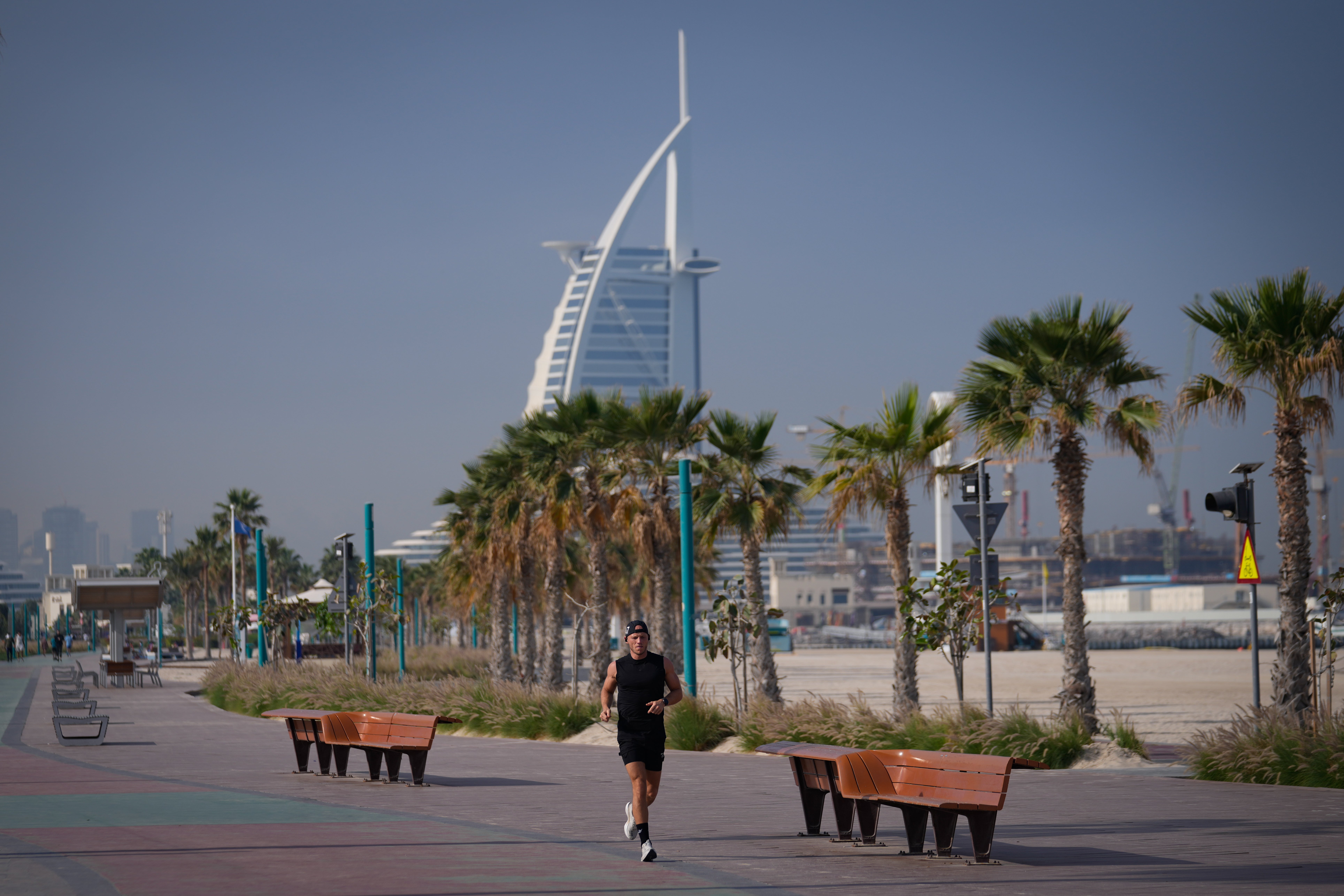 A man jogs along a beach with the Burj Al Arab luxury hotel seen in the background in Dubai, United Arab Emirates, Sunday, March 1, 2026.