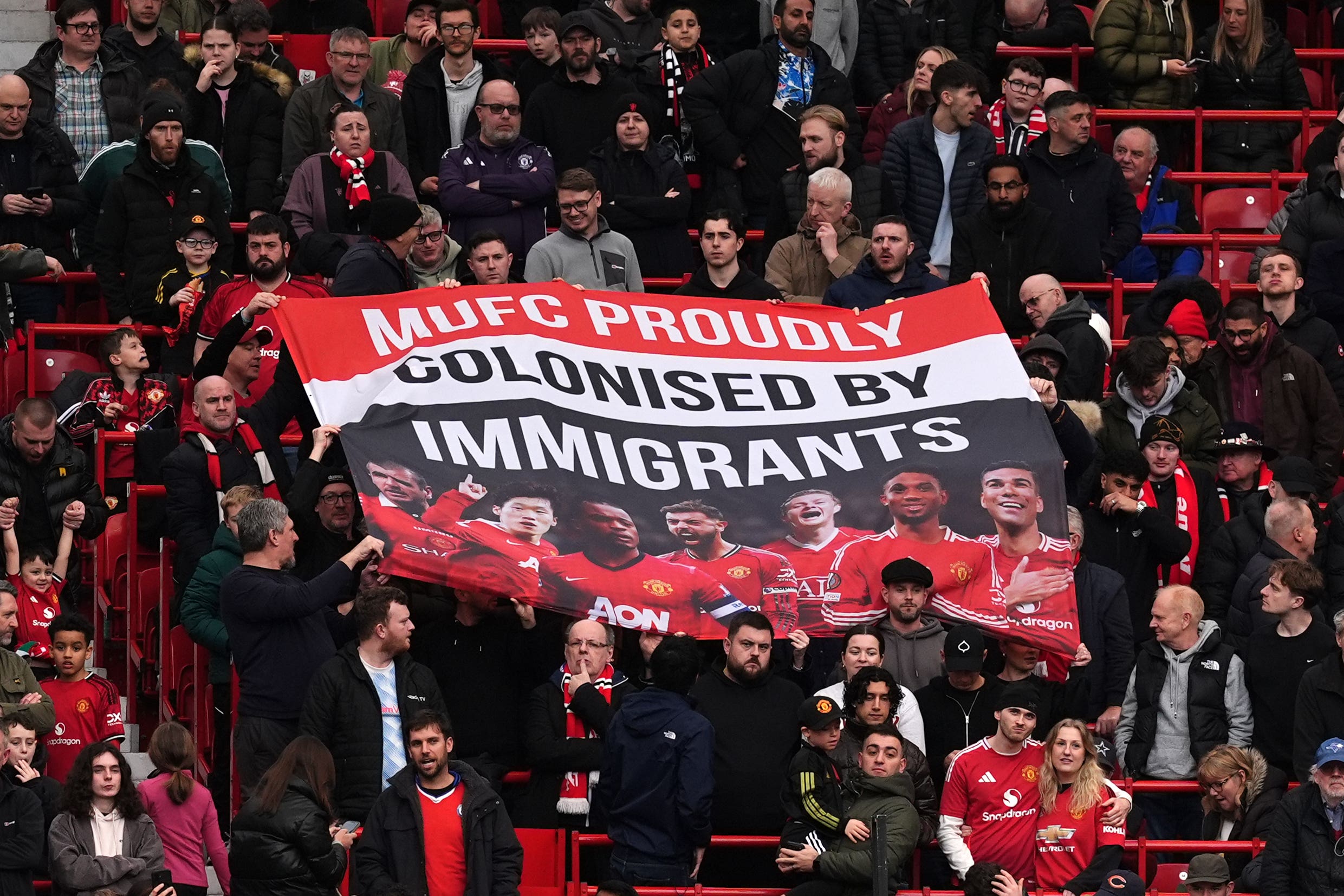 Manchester United fans hold up a banner reading ‘MUFC proudly colonised by immigrants’ during the match against Crystal Palace at Old Trafford (Martin Rickett/PA)