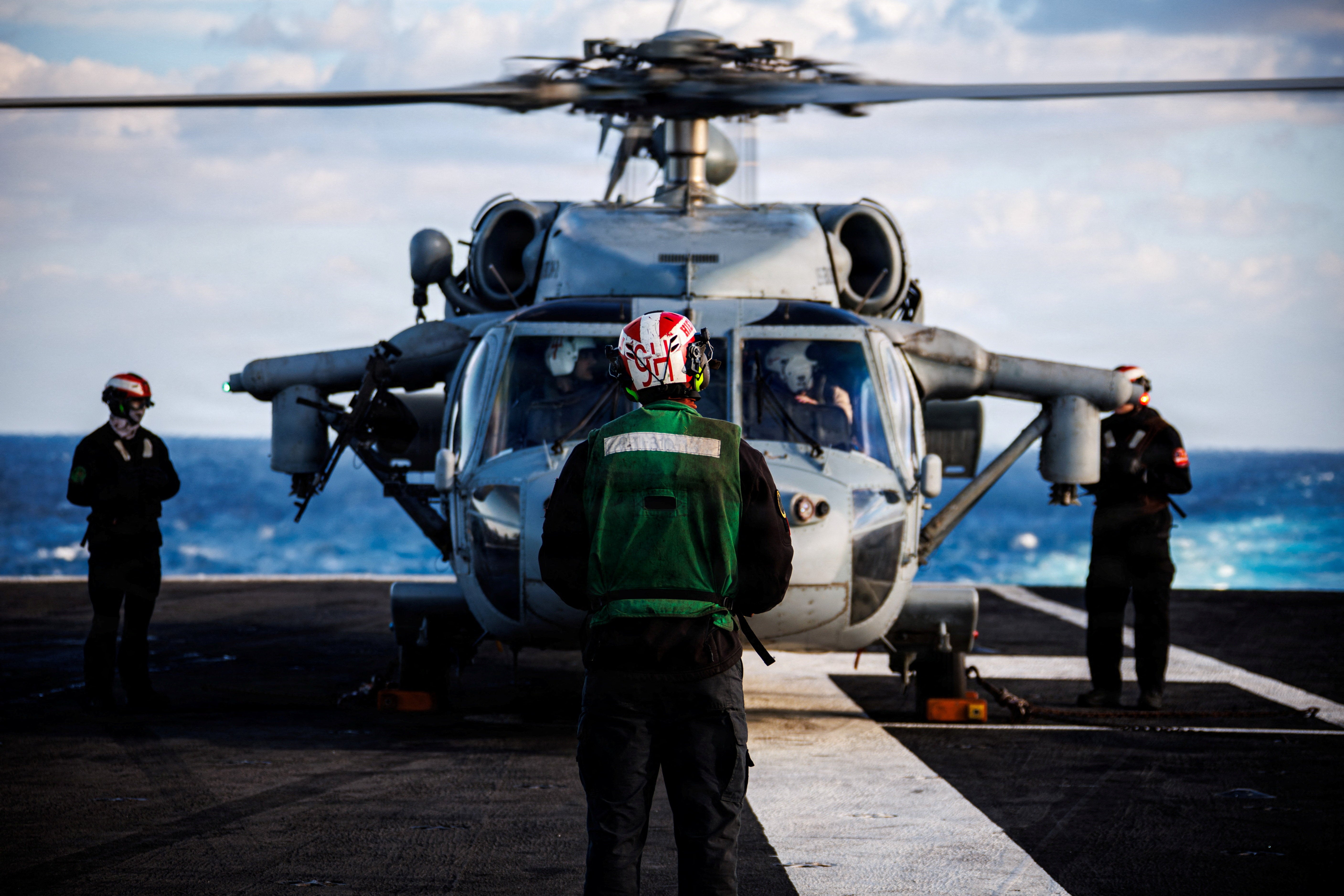 A US Navy sailor prepares an MH-60S Sea Hawk helicopter for launch on the flight deck of the aircraft carrier USS Gerald R Ford